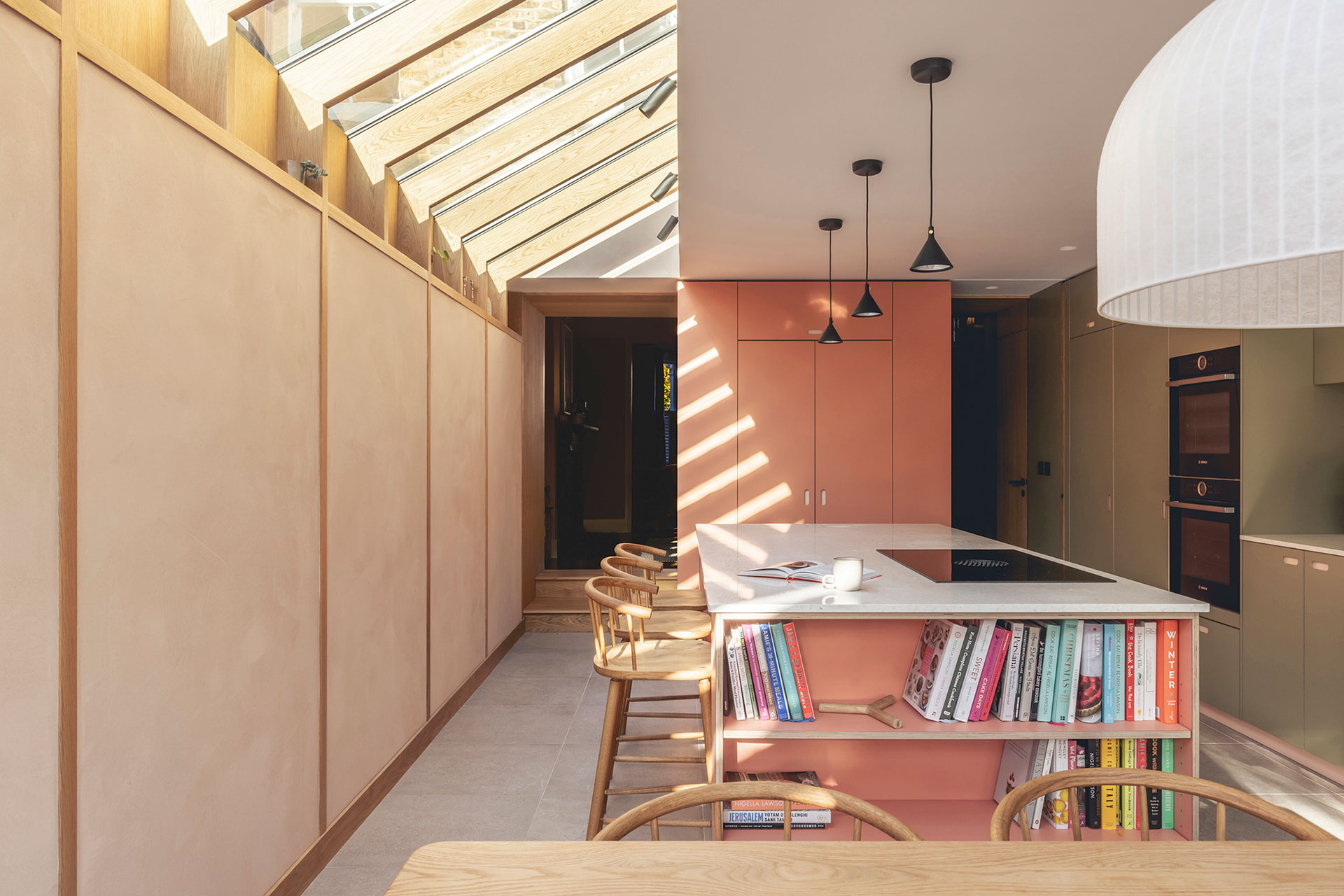 Pink and green open plan Pluck kitchen including an island with clay plaster walls and Oak wood beams.