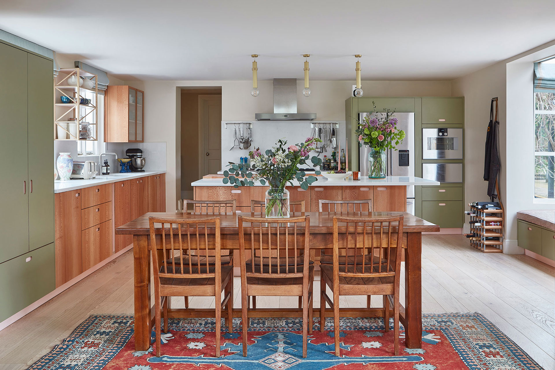 Soft green, pale pink and London Plane wood cabinetry with a kitchen island, serious cooking kit and dining table.