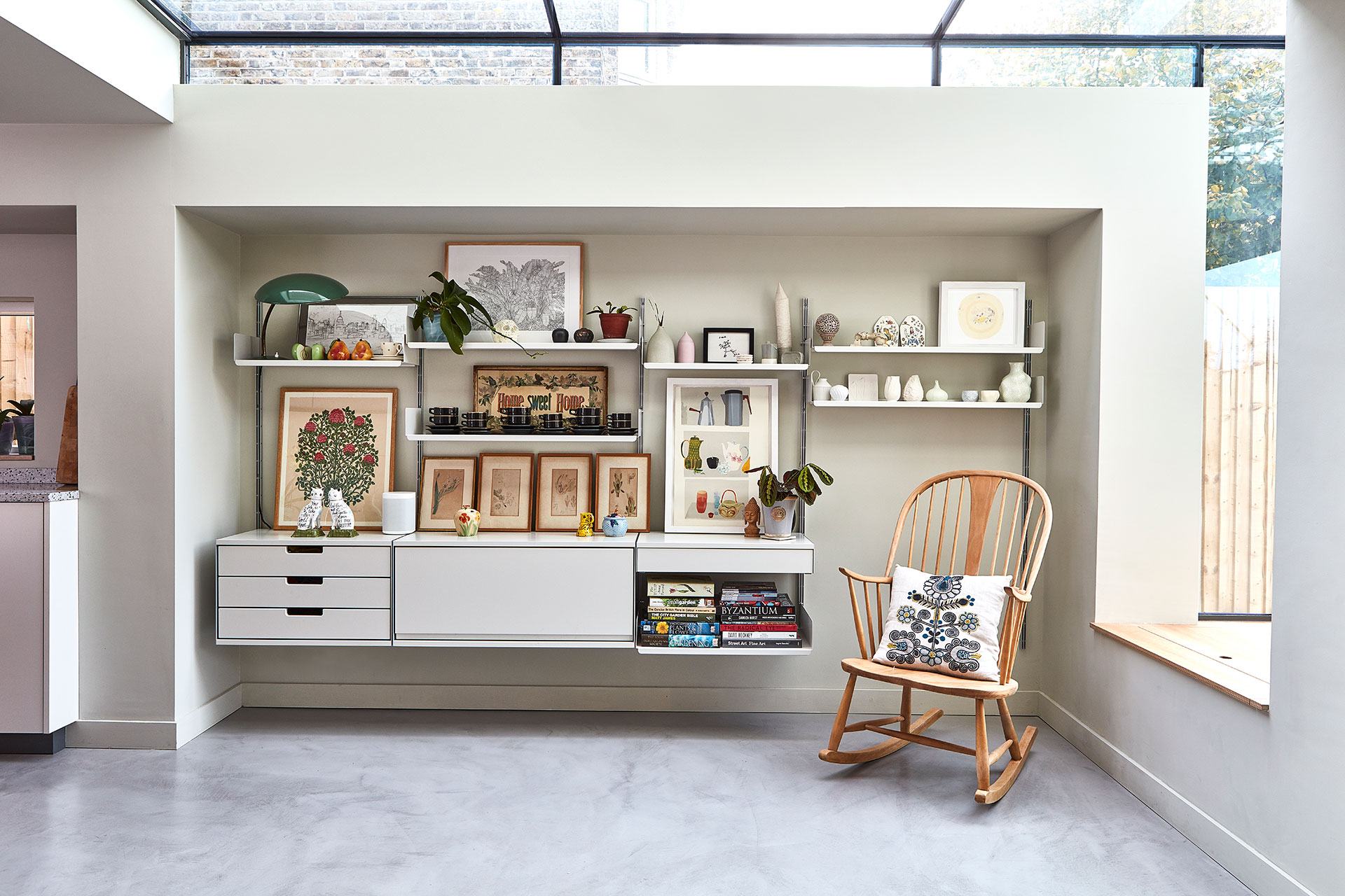 Cosy reading nook with a vintage rocking chair and a shelving unit displaying antiques.
