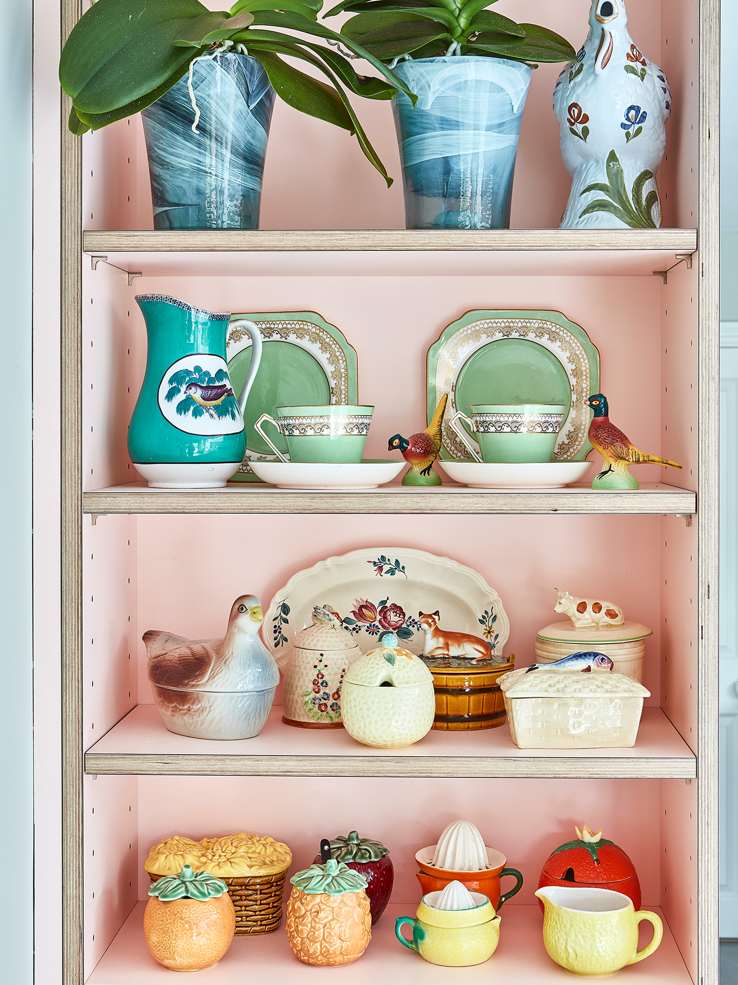 Pink kitchen shelving with curated antiques and vintage ceramics.