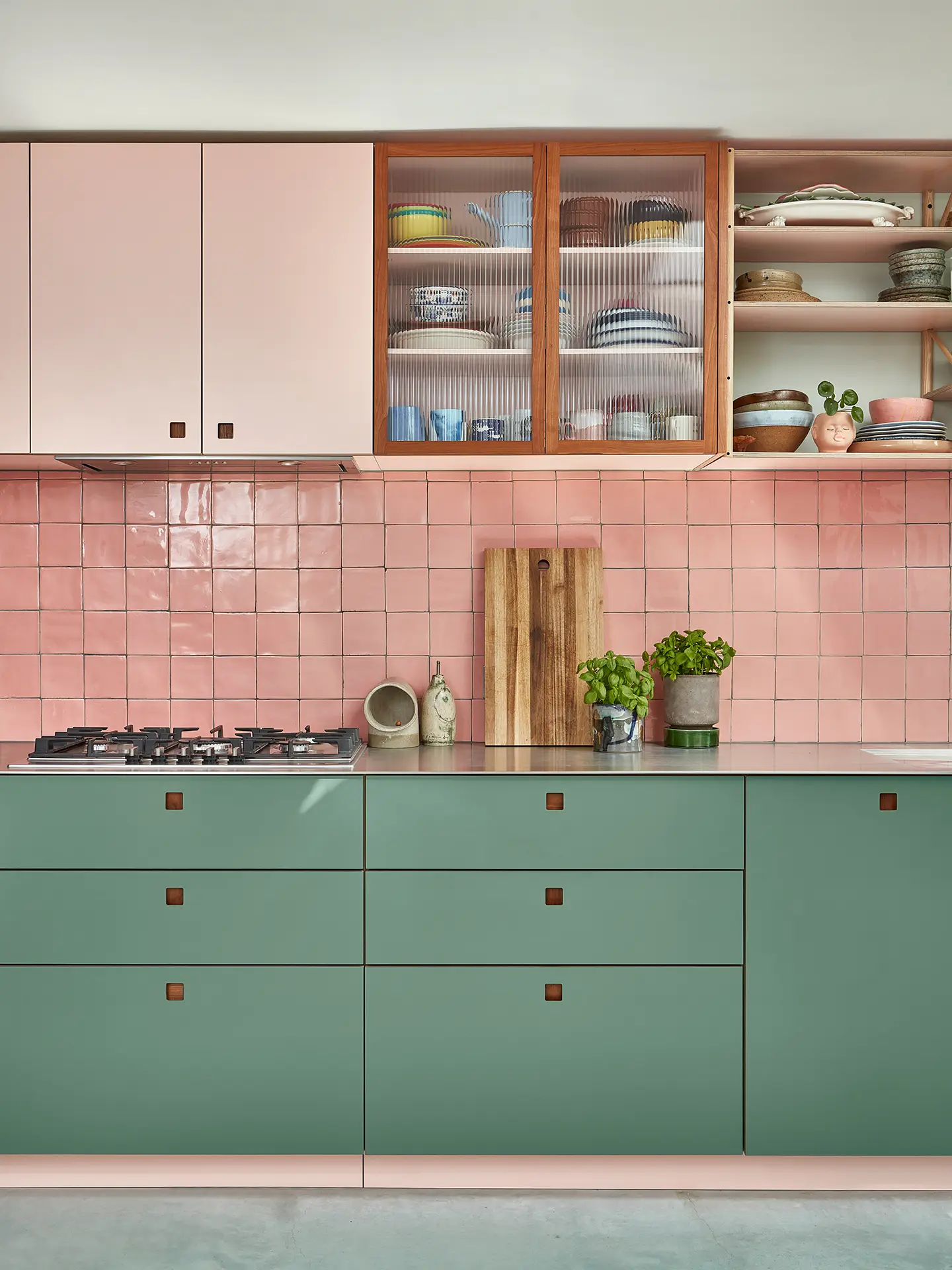 Sleek stainless steel topped pink and green cabinetry with a wooden kitchen table.