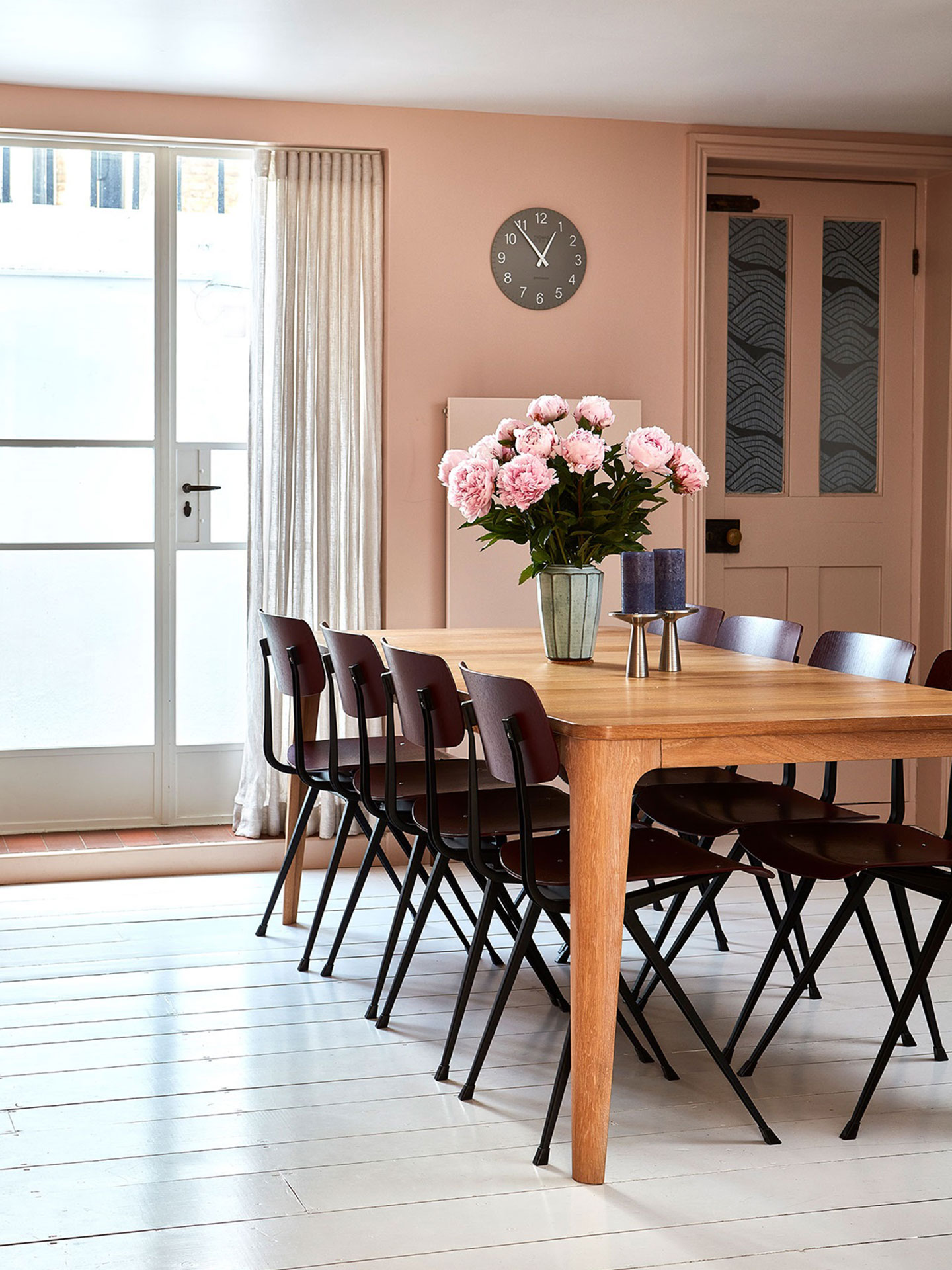 Wooden dining table with blush pink walls.