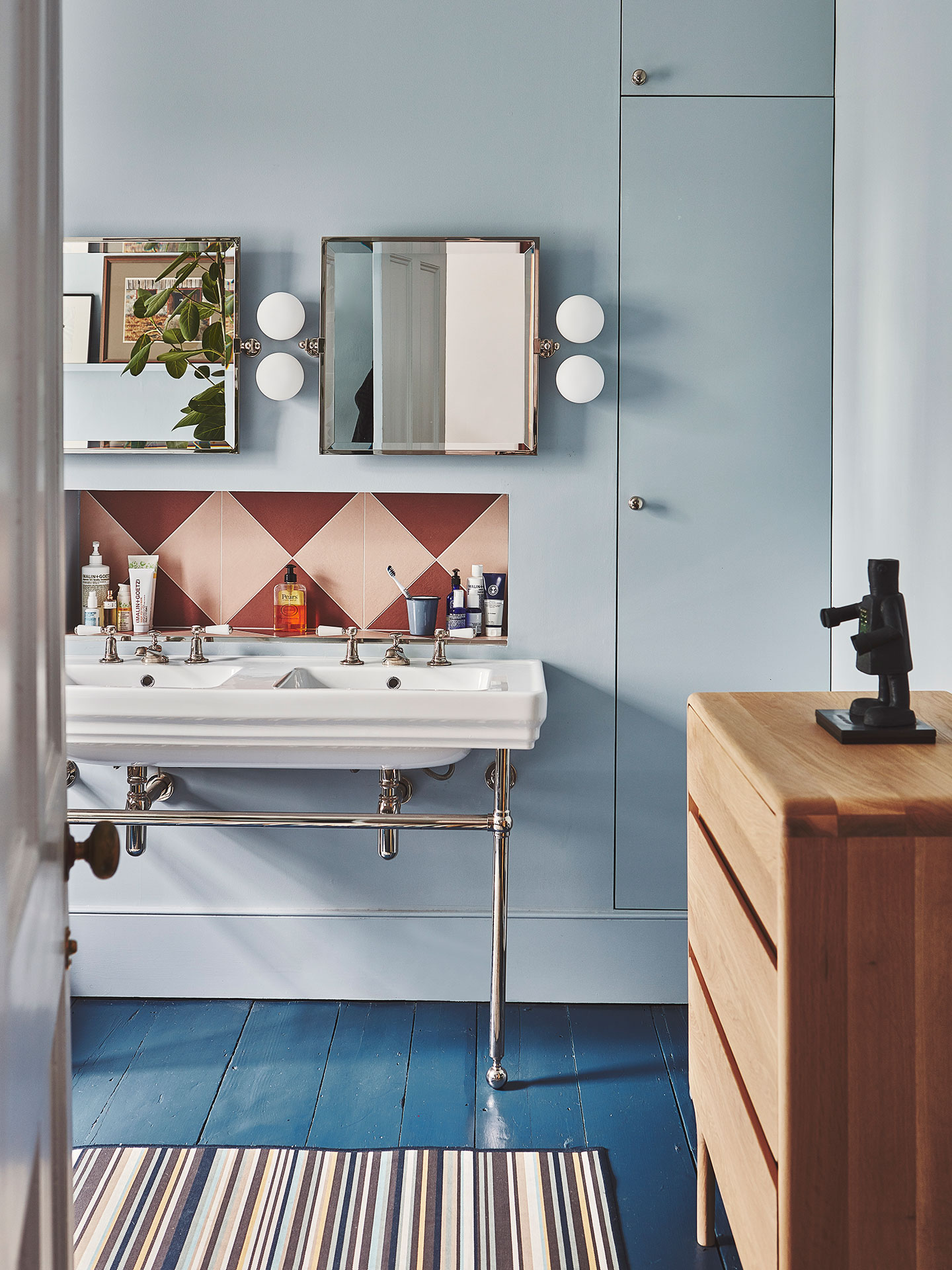 Light blue bathroom with double sink and pink tiles.