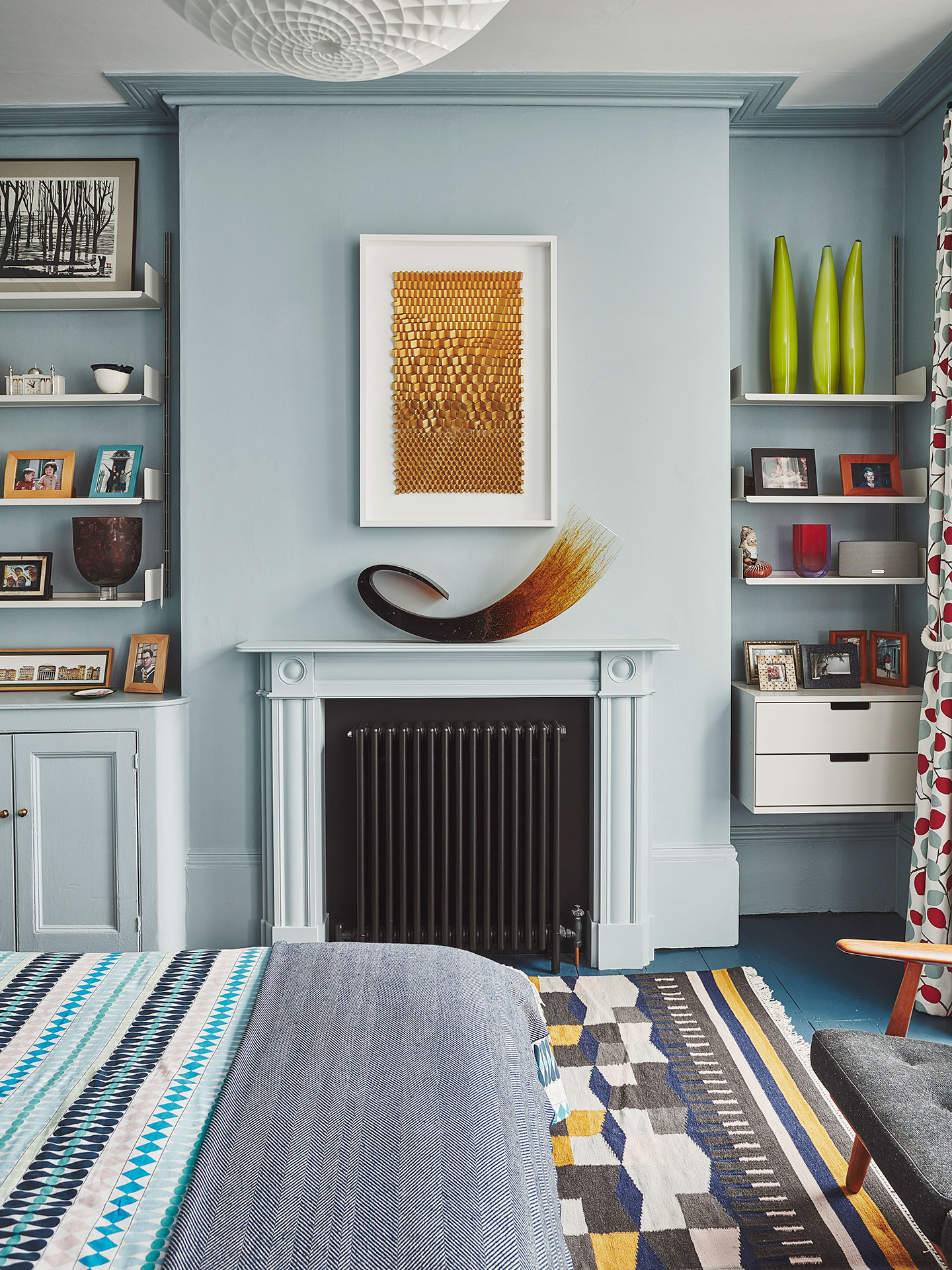 Baby blue bedroom with a fireplace and shelving.