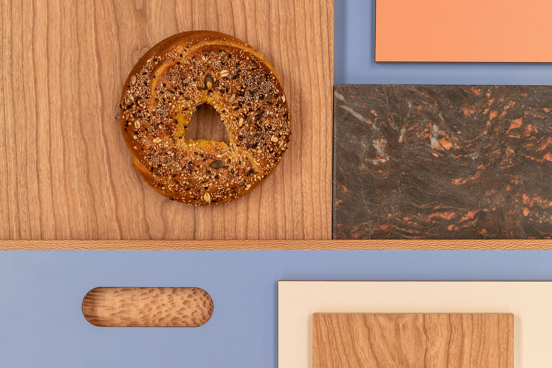 Kitchen colour and wood inspiration with warm Cherry and London Plane wood, blue, coral pink, black quartzite and a bagel.