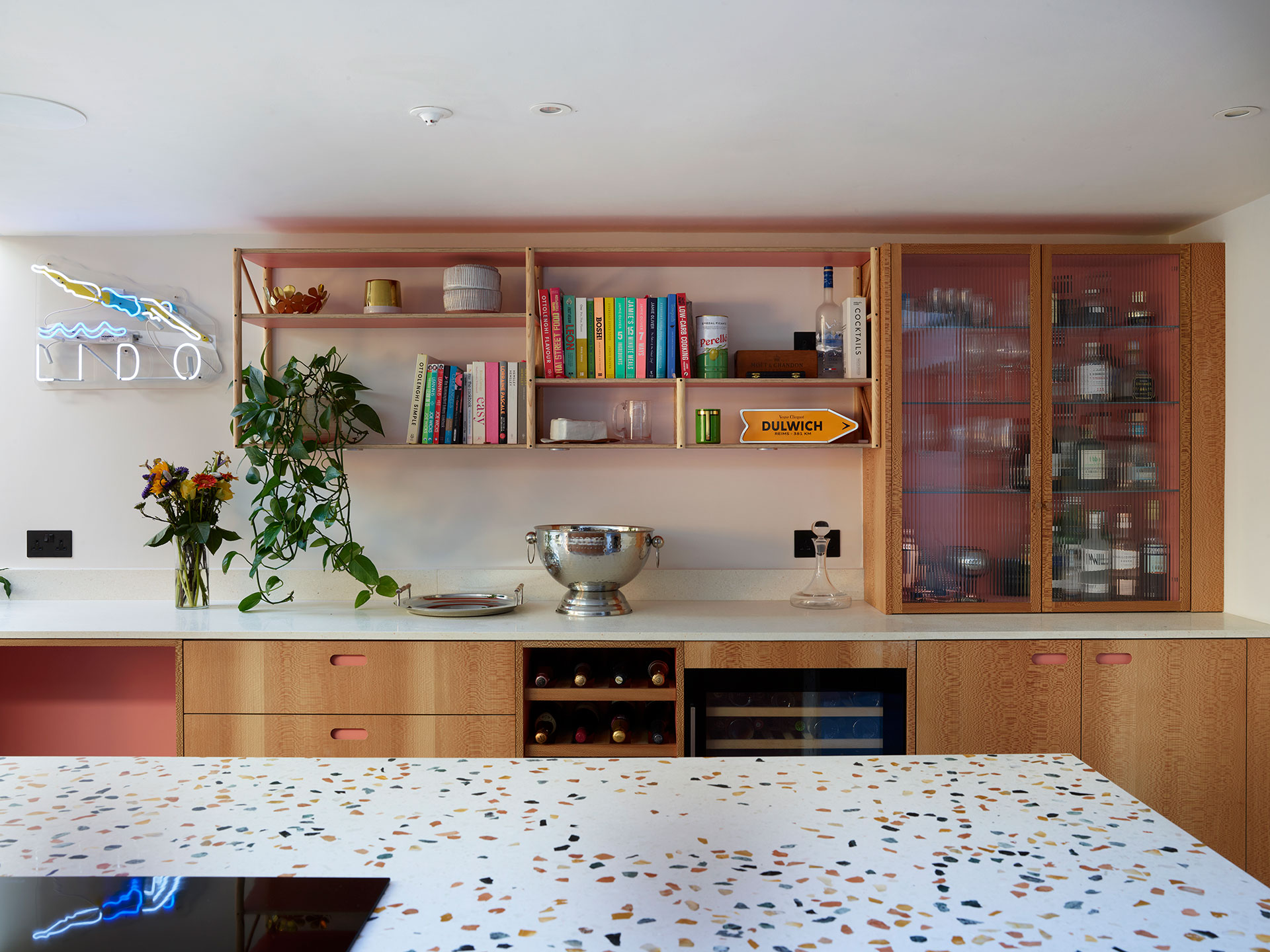 Open plan dinner party kitchen with a cocktail cabinet and terrazzo waterfall edge island.
