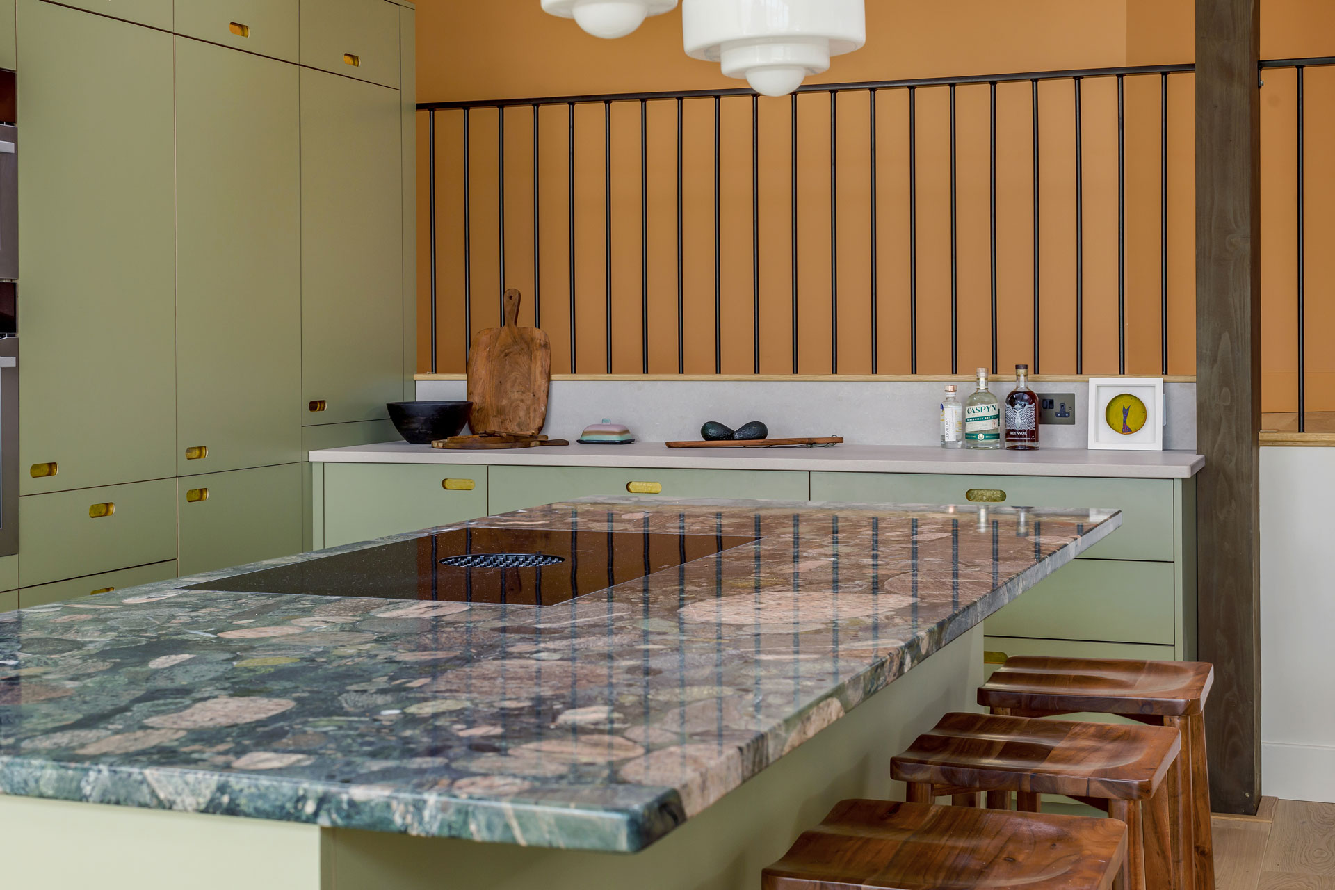 Open plan green kitchen with brass handles and stunning granite worktop in Padstow.