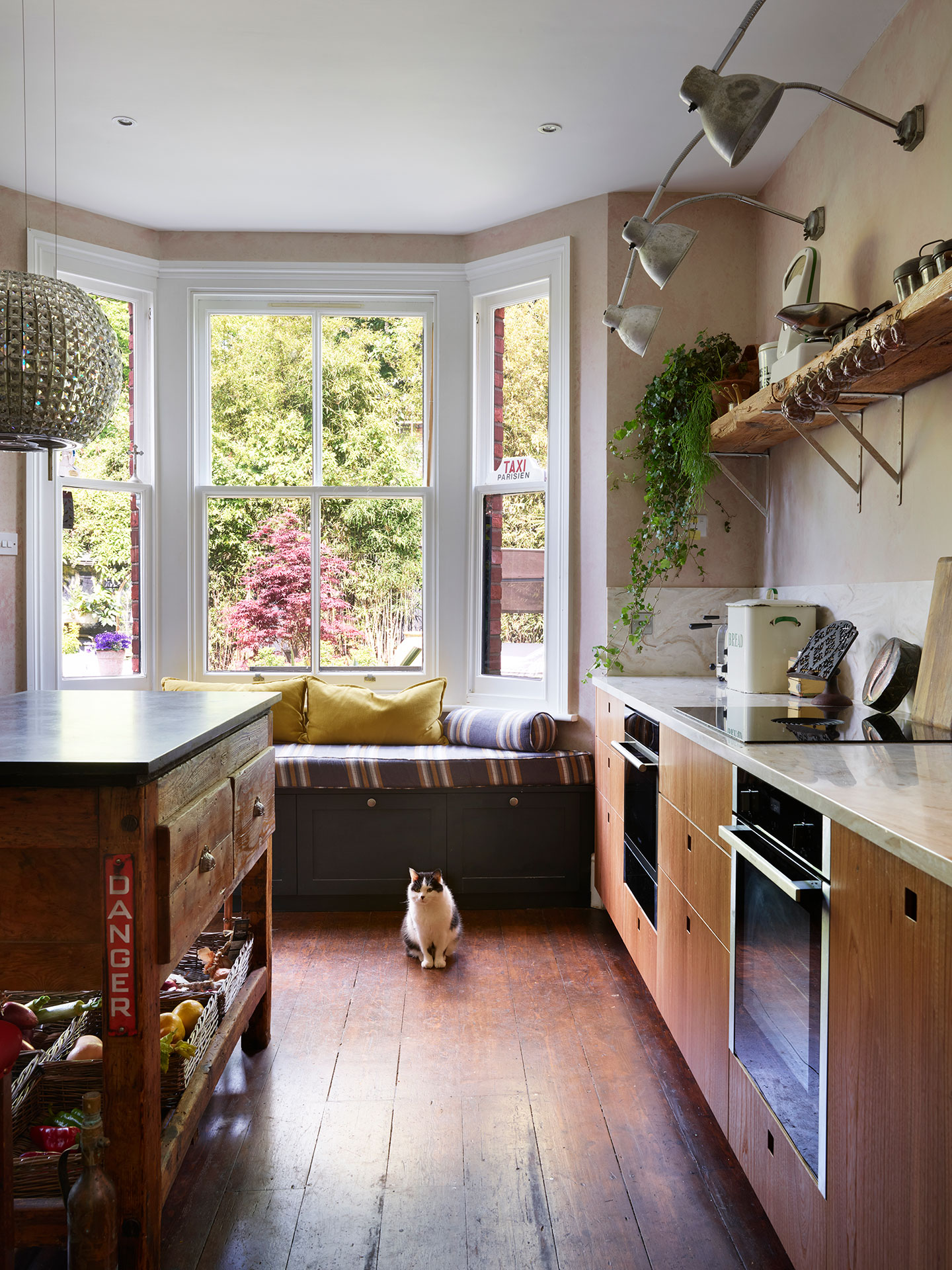 Moody kitchen including Elm wood and khaki cabinetry in an open plan space with a vintage typesetting table island and antiques.