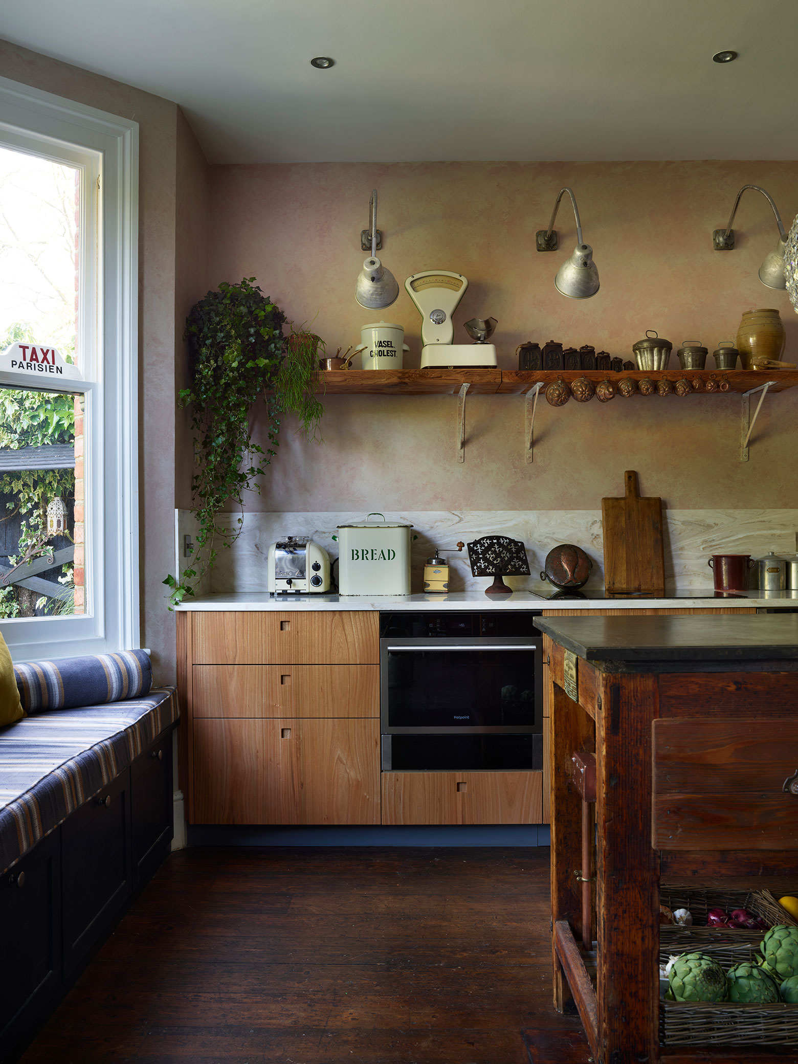 Moody kitchen including Elm wood and khaki cabinetry in an open plan space with a vintage typesetting table island and antiques.
