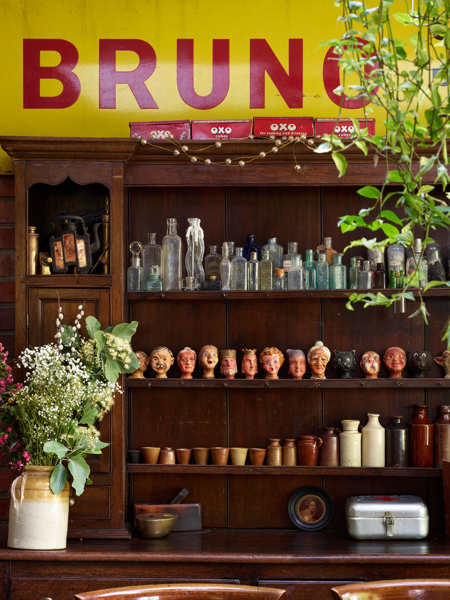 A dresser full or curiosities; bottles and ceramic heads.