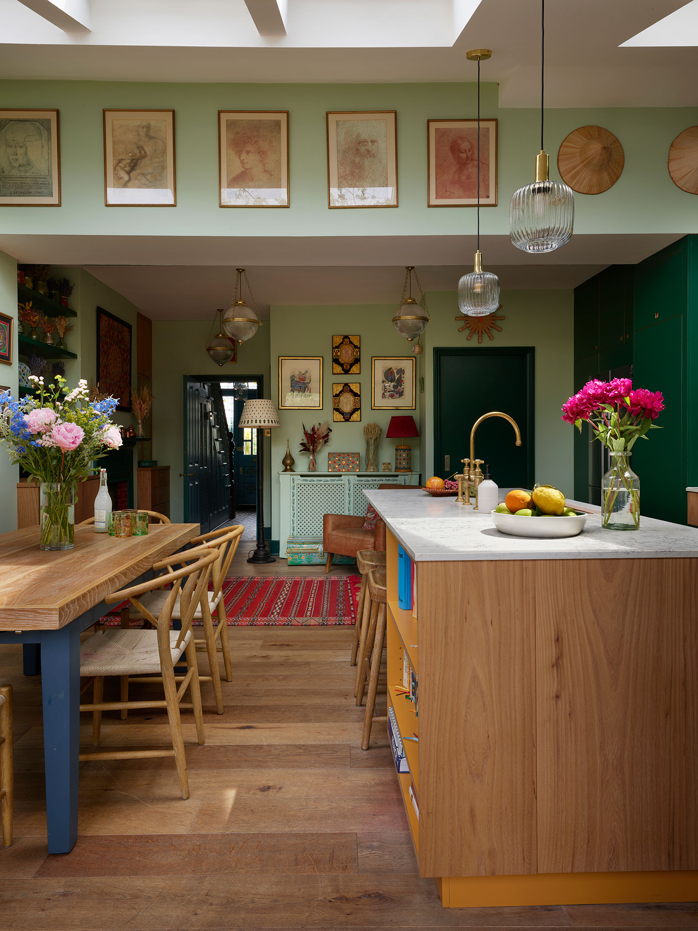 Kitchen home to an artist including dark green, Elm wood and mustard yellow cabinets, glossy tiles and pale palm green walls.