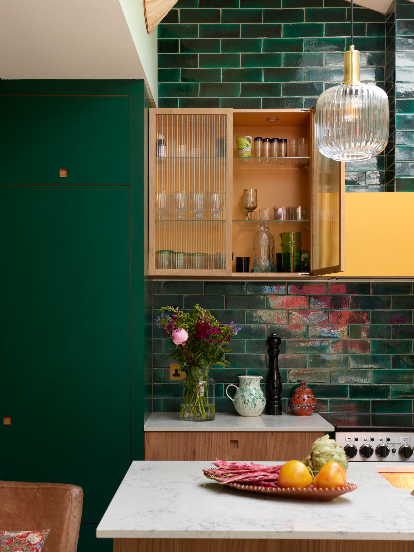 Colourful open plan Pluck kitchen with green, yellow and wood cabinets, home to an artist.