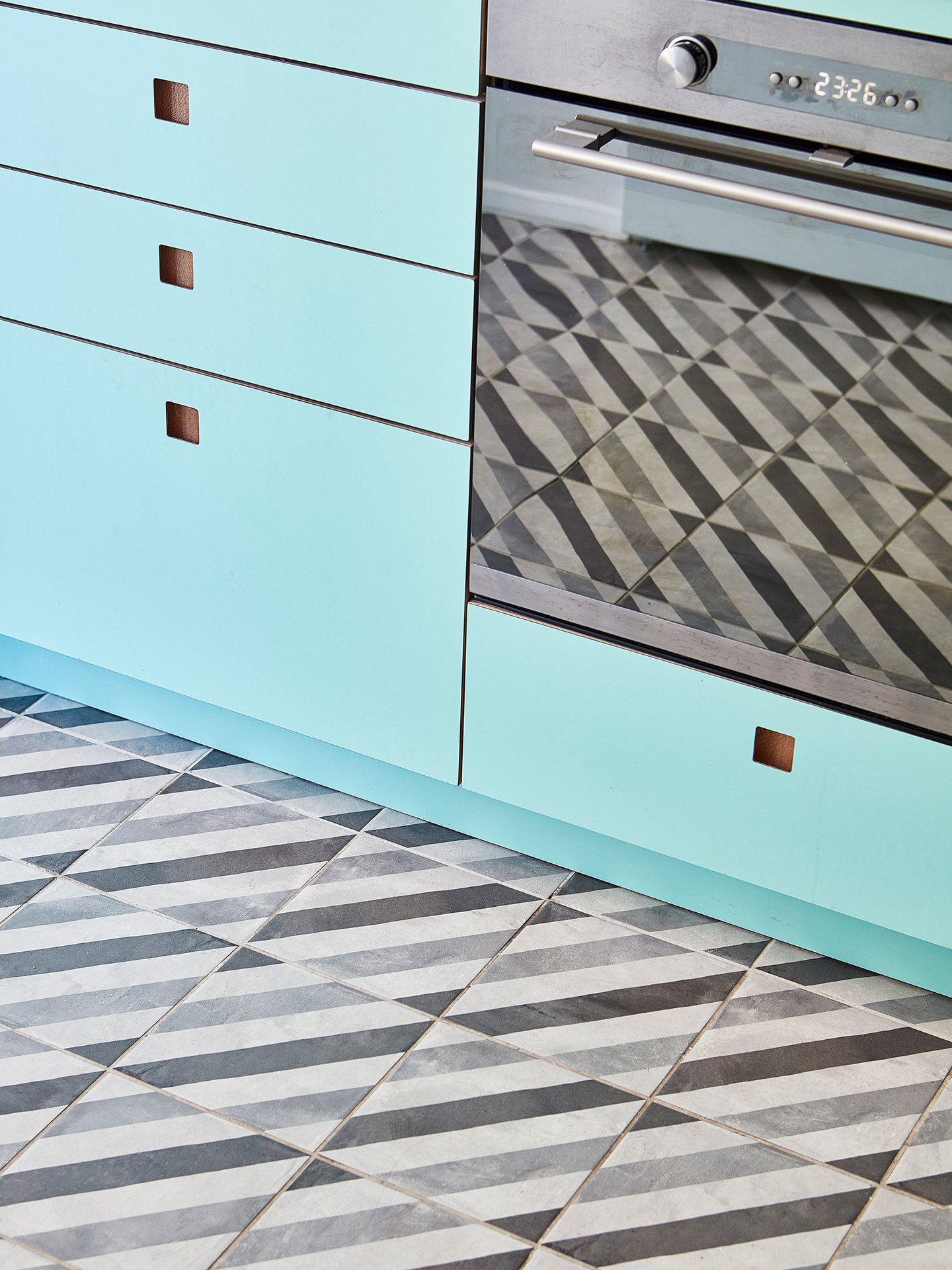 Close up of a mint green kitchen with geometric floor tiles