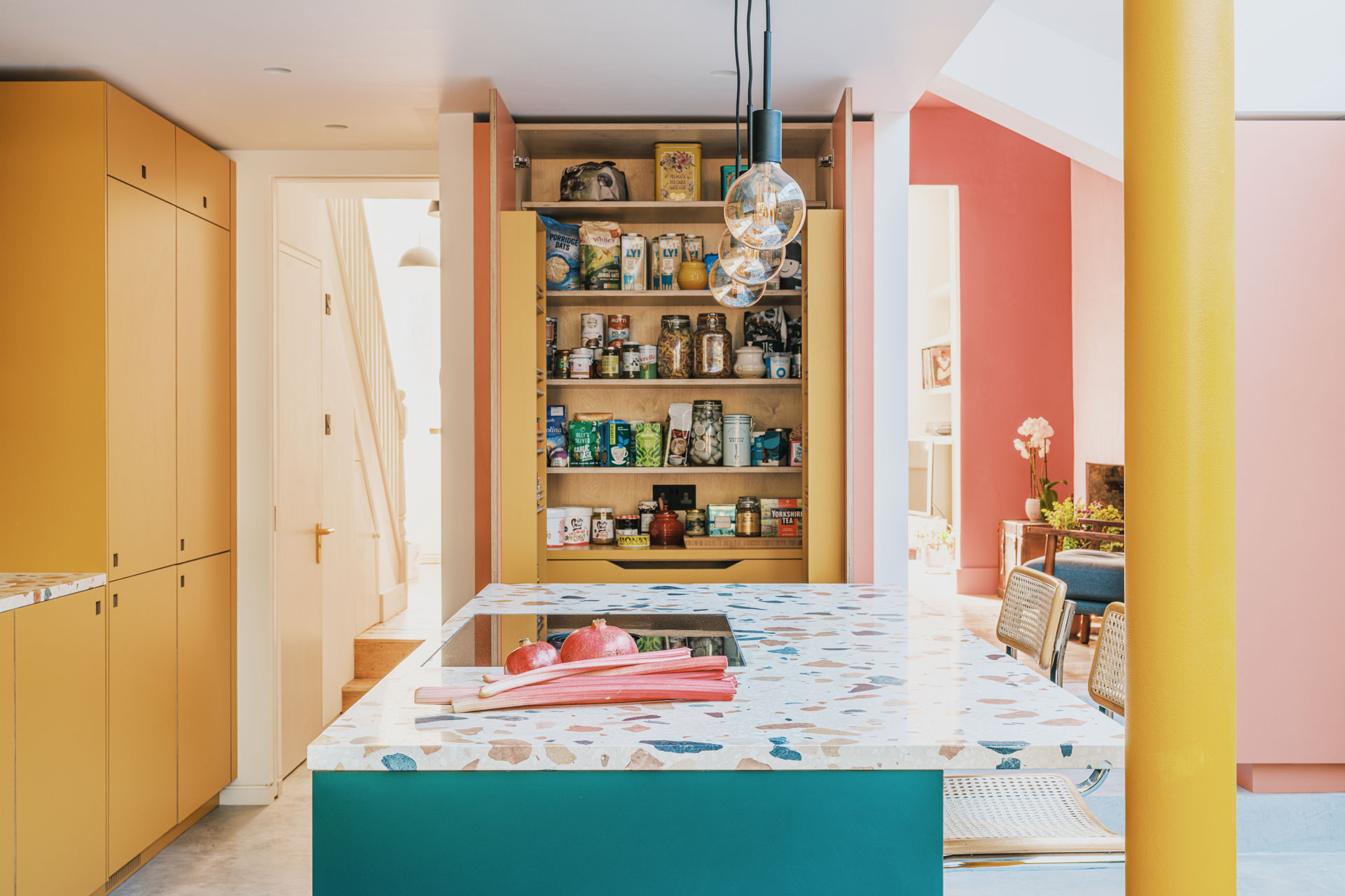 Colourful kitchen with a terrazzo topped island, shelving, dresser and banquette seating.