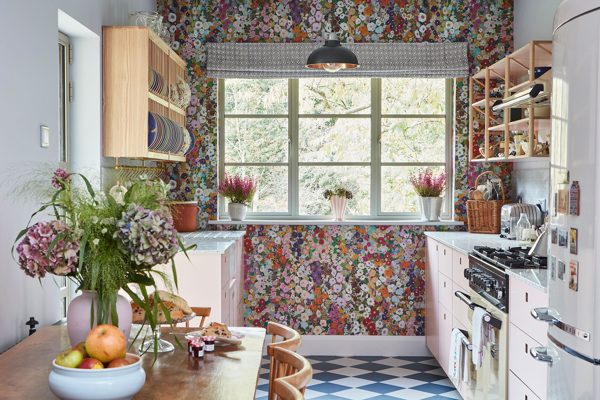 Pretty cottage kitchen in Epping Forest with soft pink cabinets, floral House of Hackney wallpaper and checkerboard floor.