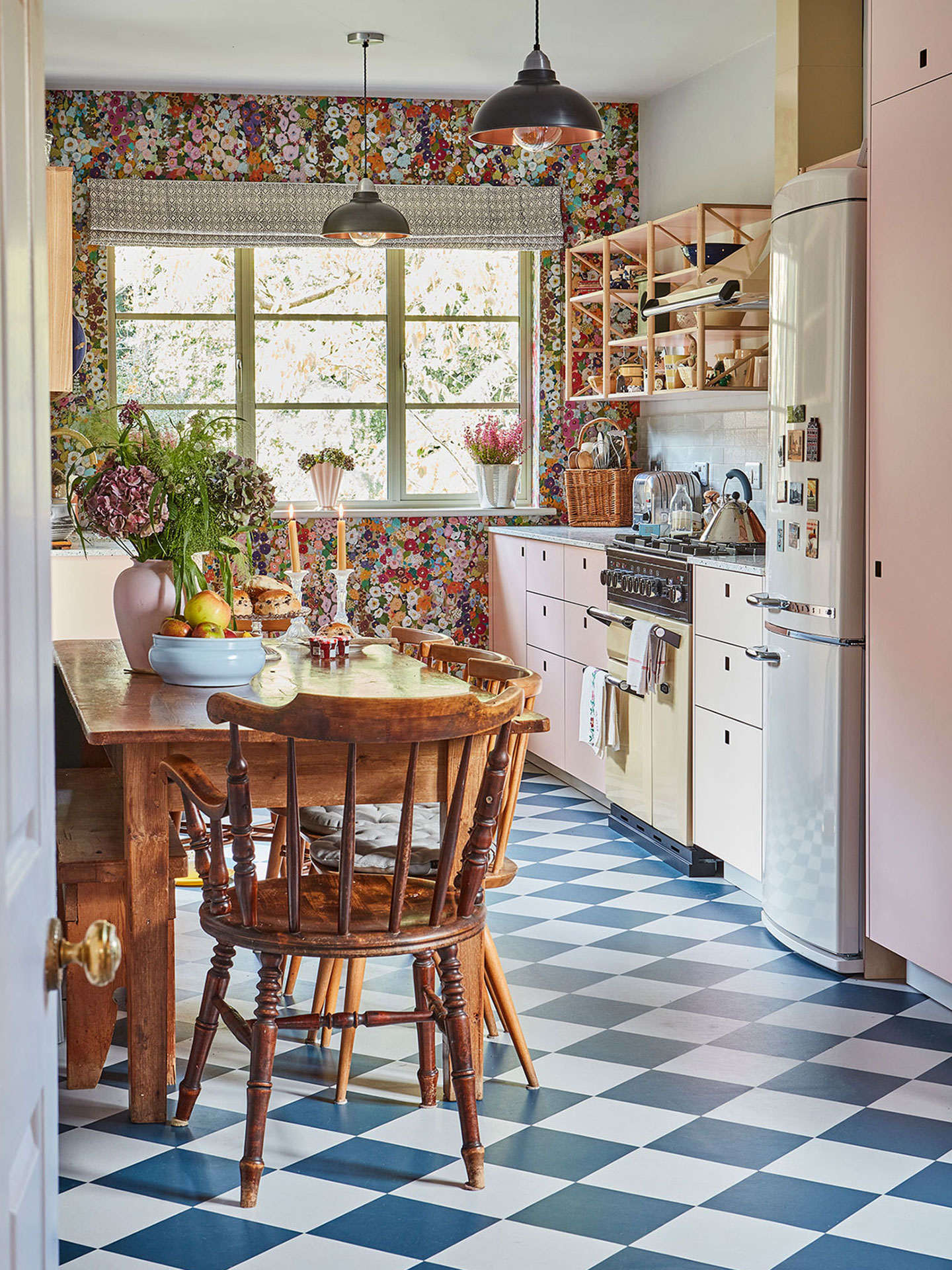 Pretty cottage kitchen in Epping Forest with soft pink cabinets, floral House of Hackney wallpaper and checkerboard floor.