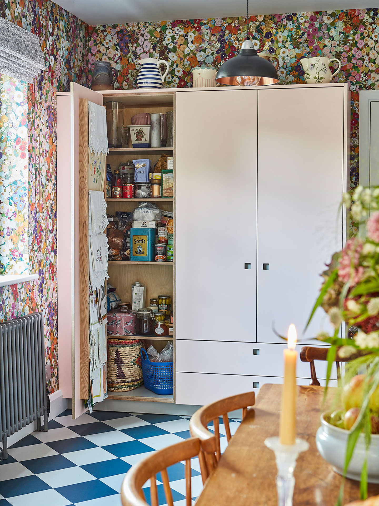 Pretty cottage kitchen in Epping Forest with soft pink cabinets, floral House of Hackney wallpaper and checkerboard floor.