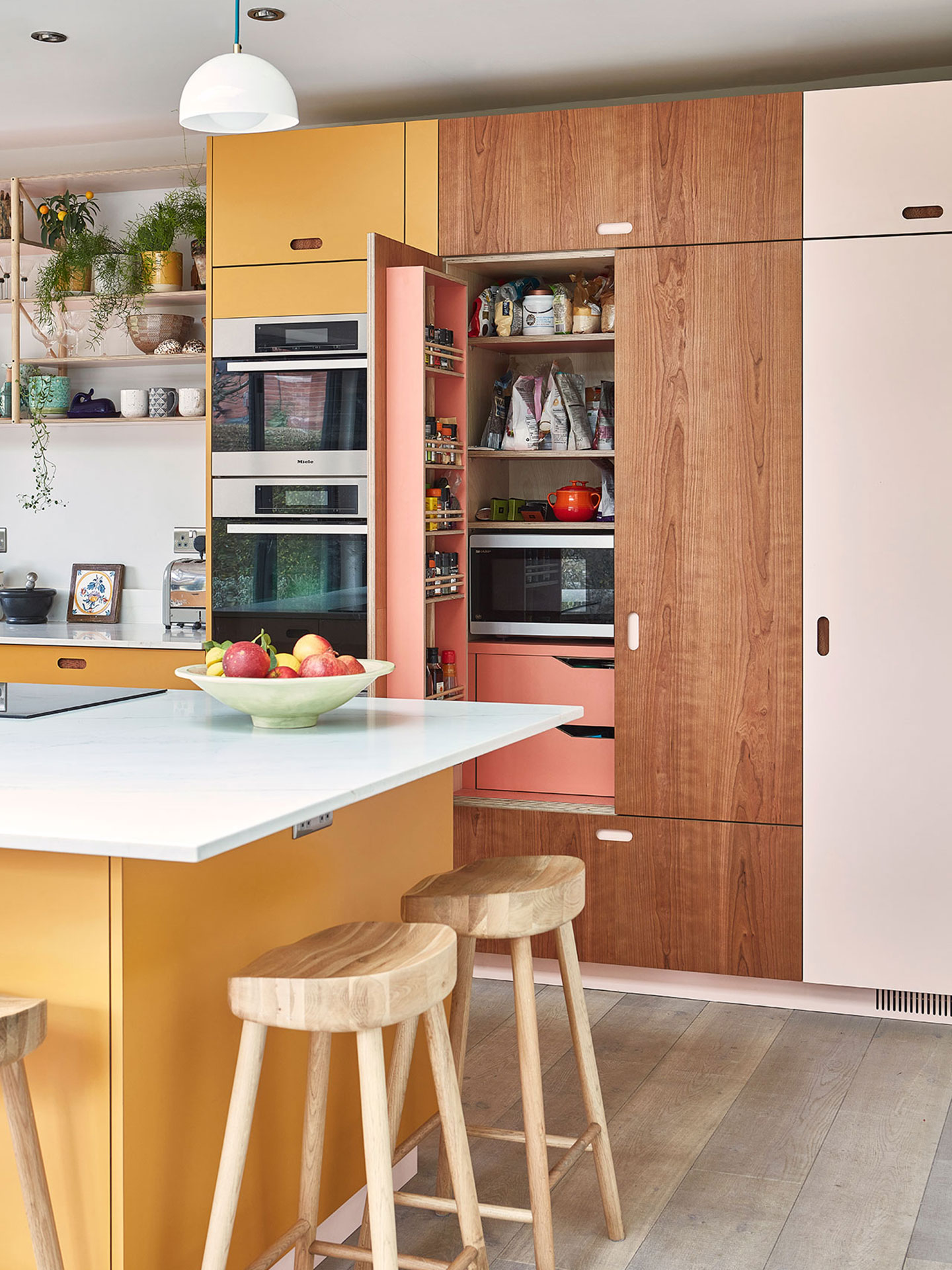 Colourful family kitchen in Birmingham including soft pink, mustard yellow and Cherry and London Plane wood Pluck cabinets.