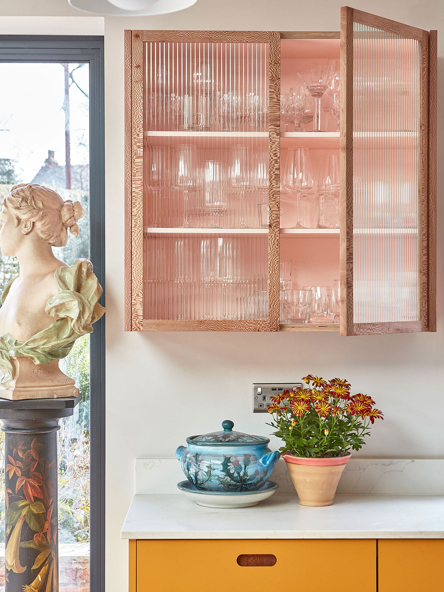Fluted glass cabinet in a family kitchen in Birmingham with a colourful palette including warm woods.