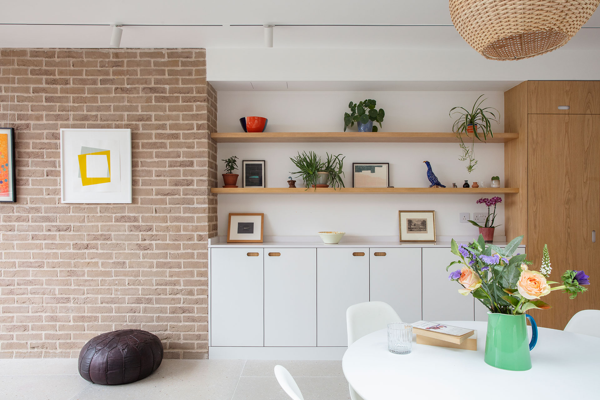 Wood, white and green kitchen with picture gallery shelving and a dining table.