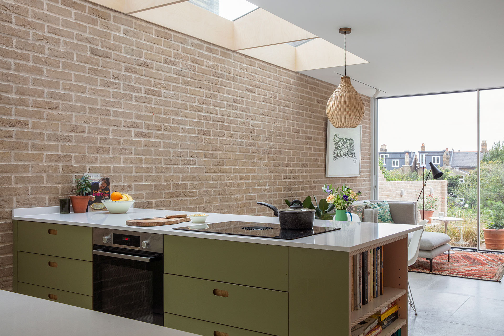 Pluck's wood, white and green cabinetry with picture gallery shelving, exposed brick walls and a circular kitchen table.