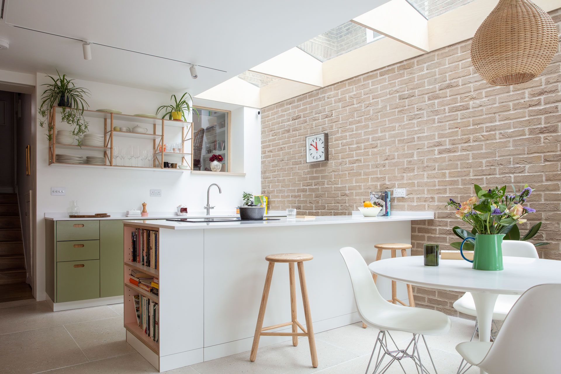 Wood, white and green kitchen with picture gallery shelving and a dining table.
