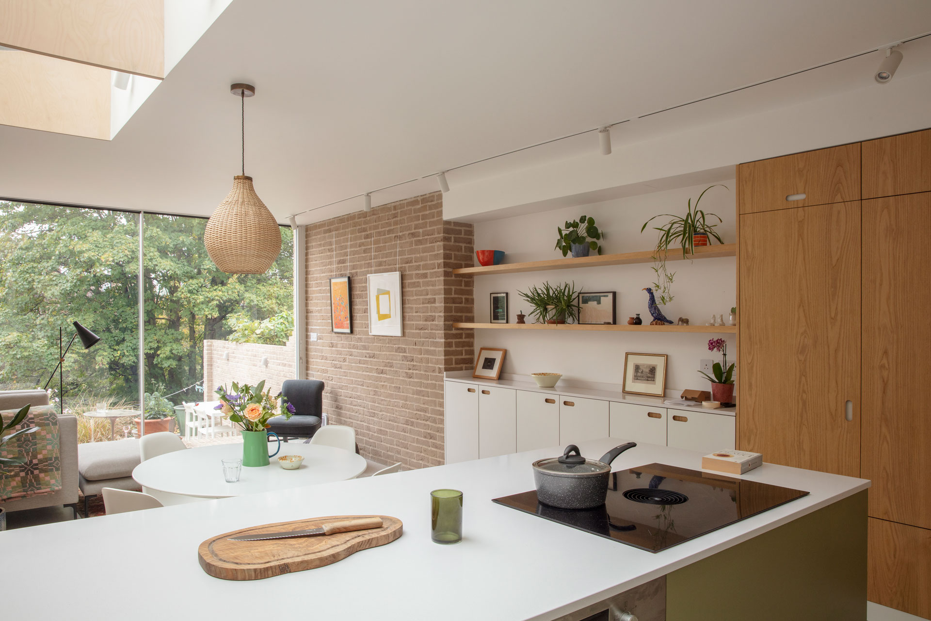 Pluck's wood, white and green cabinetry with picture gallery shelving, exposed brick walls and a circular kitchen table.