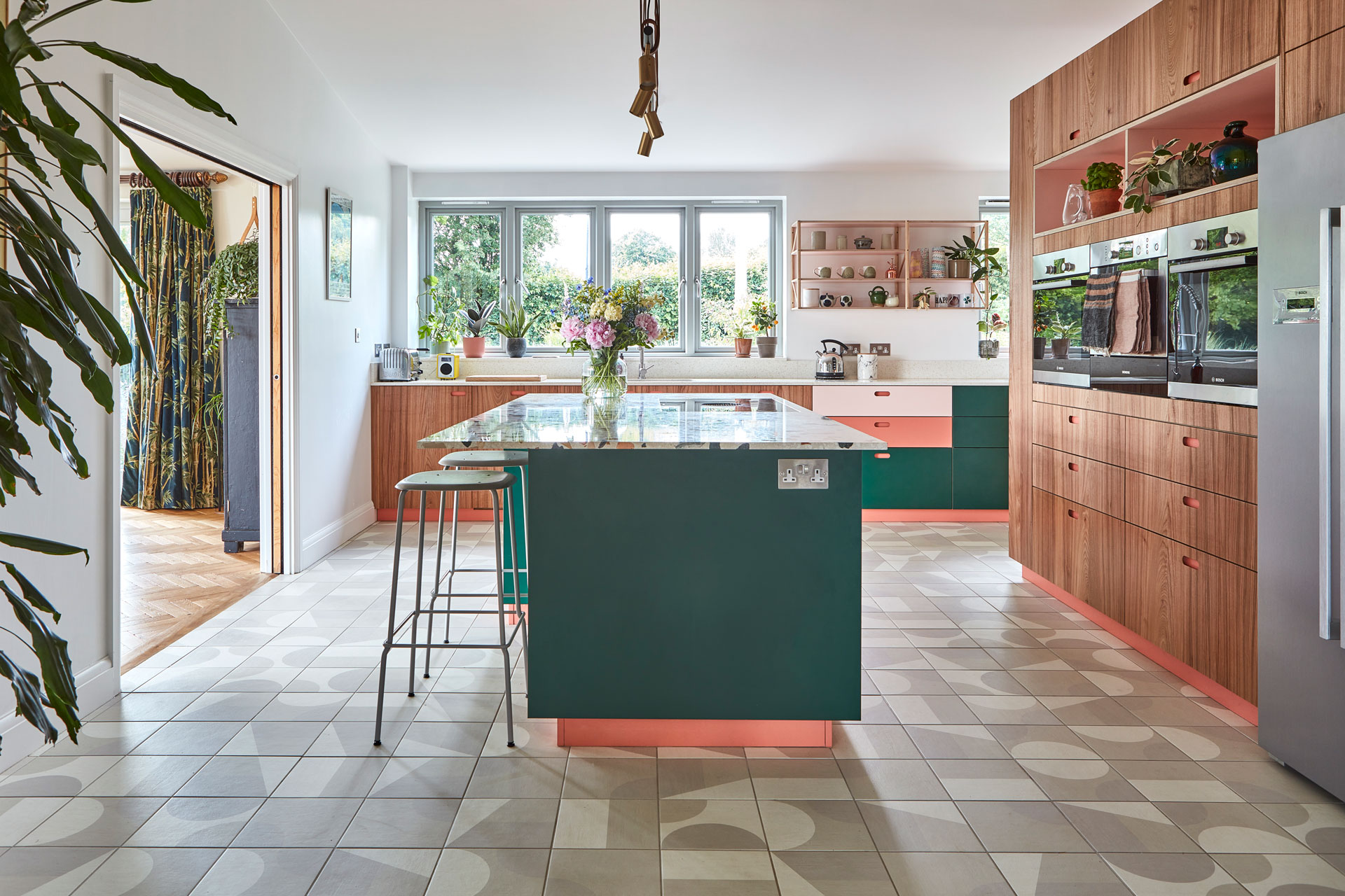 Eco house in Kent with colourful Pluck kitchen cabinets including green, pink, Elm wood and a terrazzo topped island.