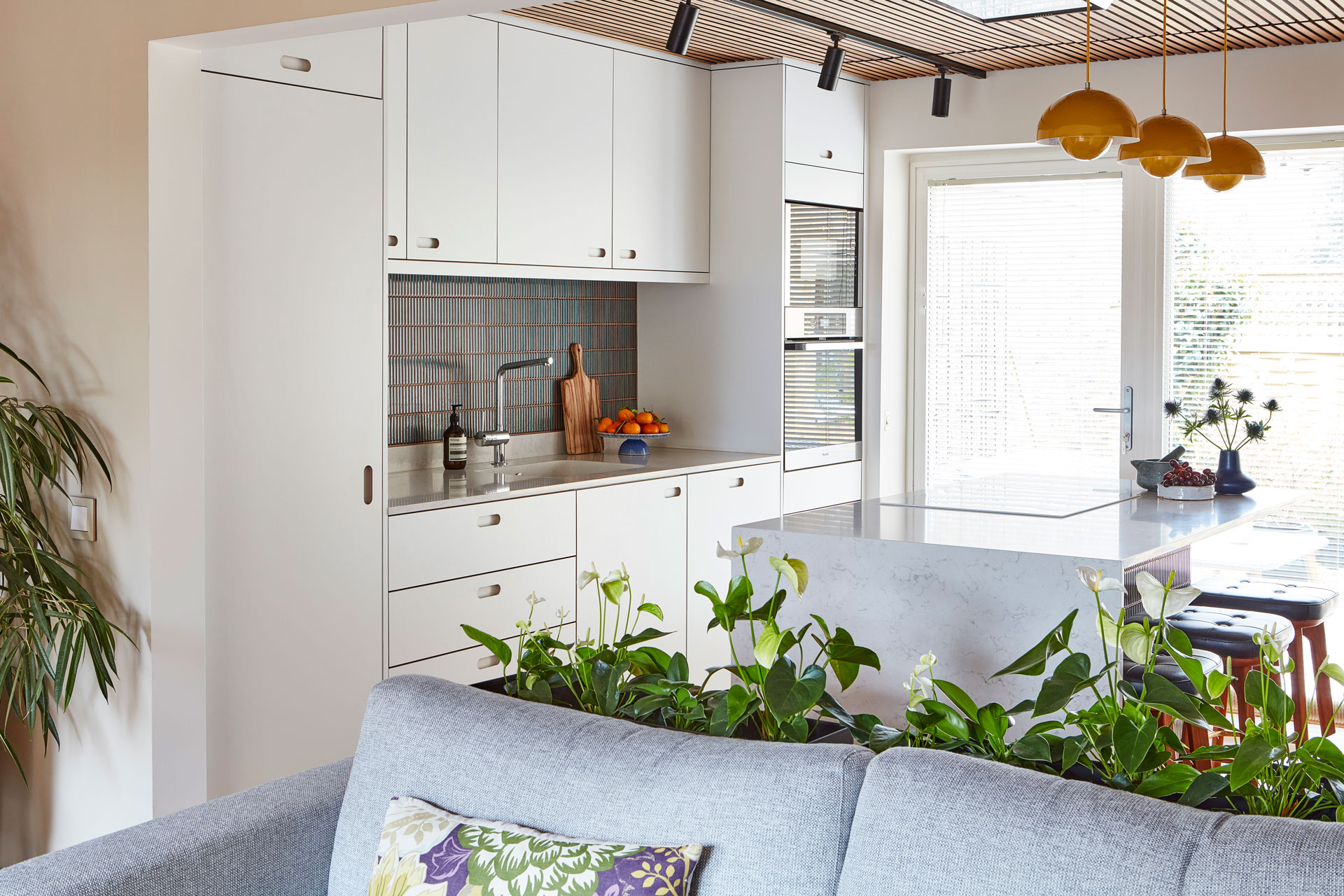 Modernist Pluck kitchen in Surrey with white cabinetry including an island.