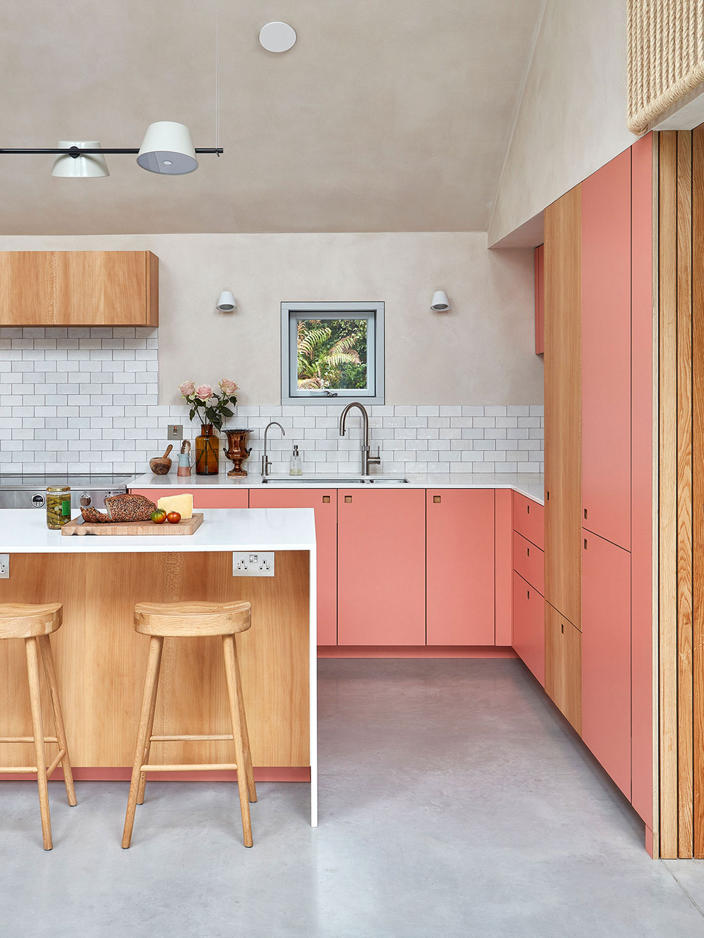 Coral pink and London Plane wood Pluck kitchen in a New Forest Eco home with a waterfall edge island.