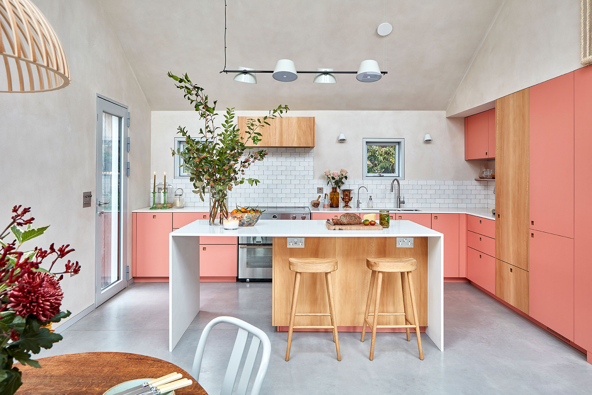 Coral pink and London Plane wood Pluck kitchen in a New Forest Eco home with a waterfall edge island.