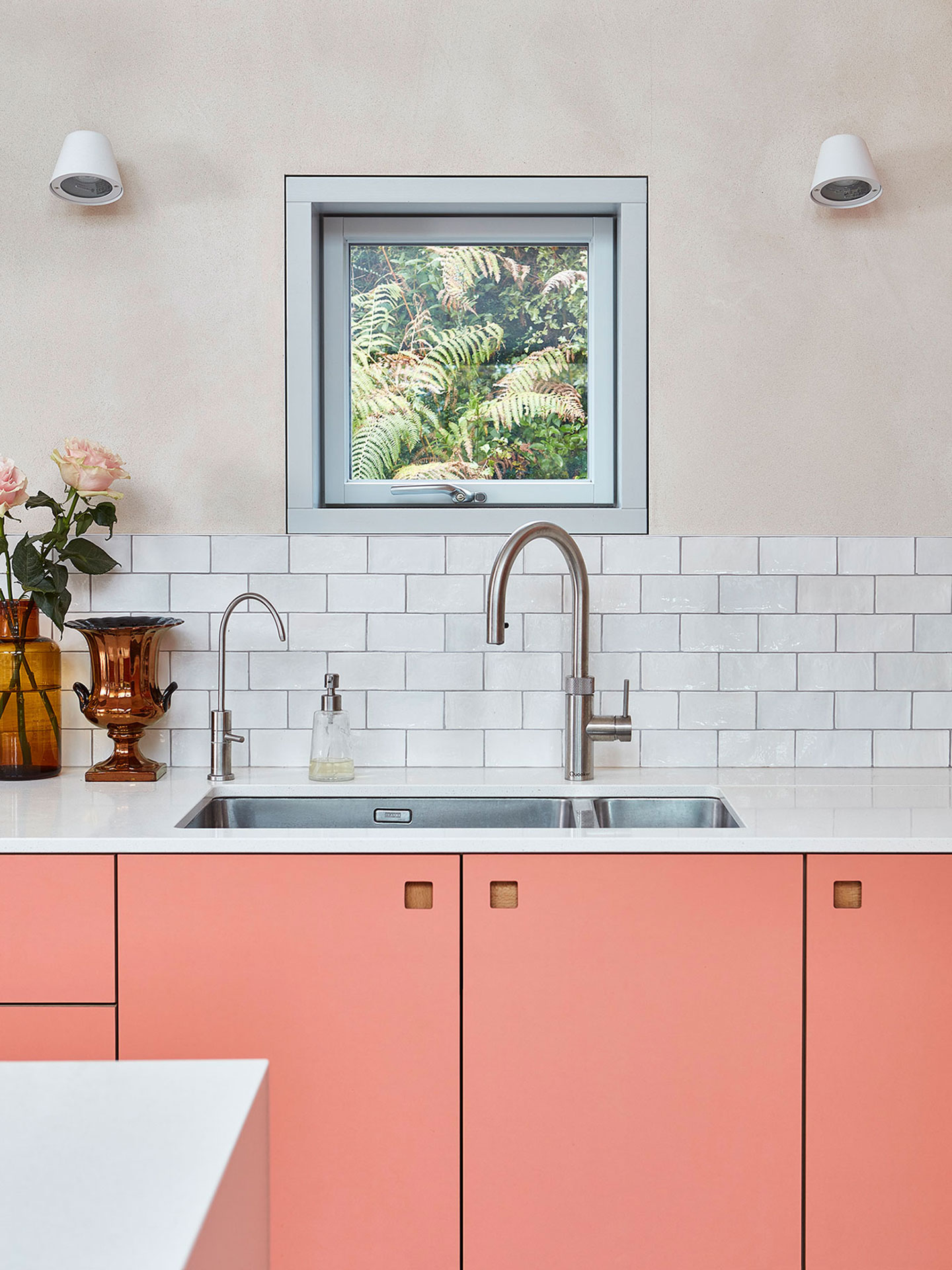 Sink view in a New Forest eco home with London Plane wood and coral pink cabinets.
