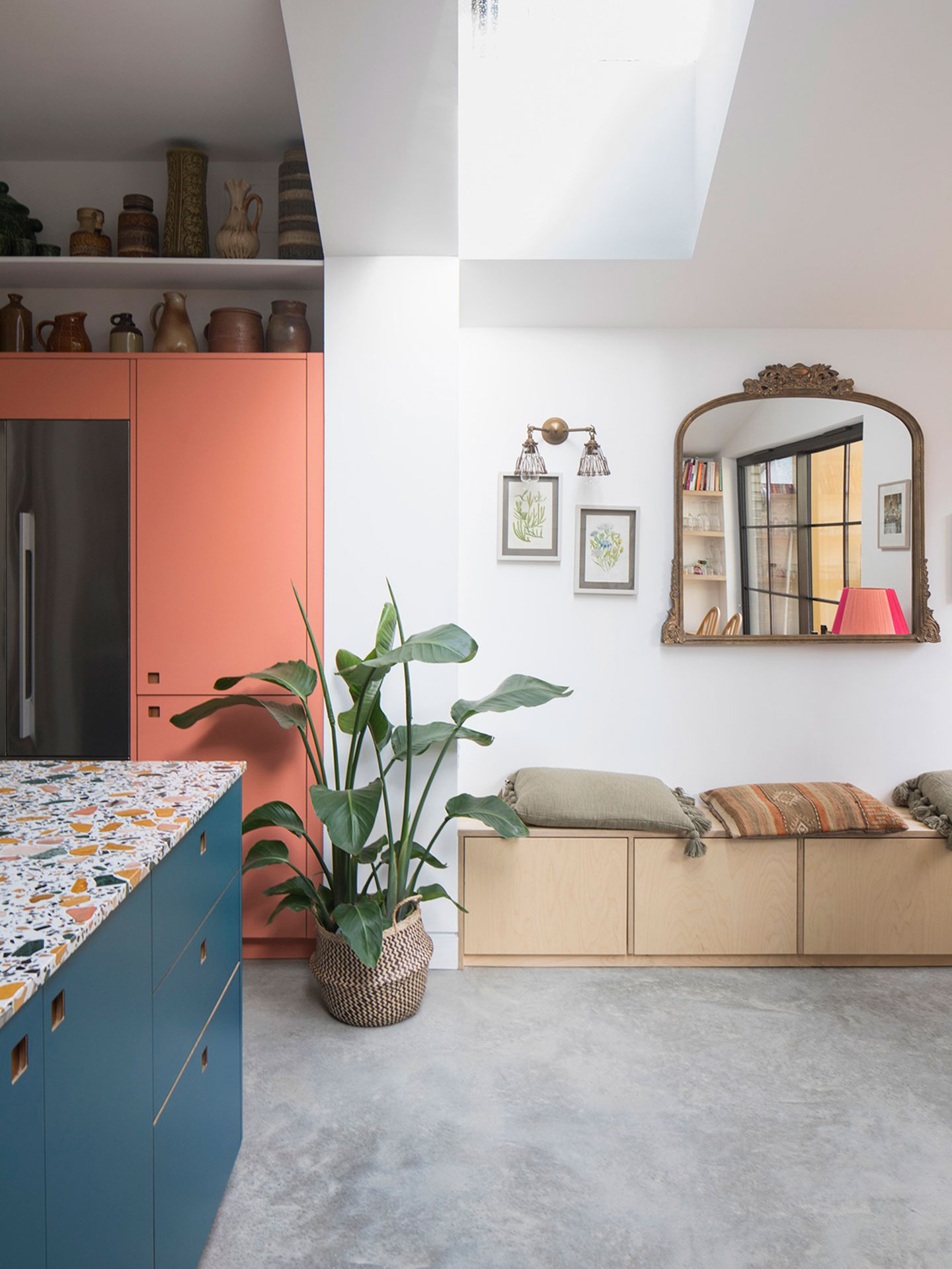 Kitchen including a rich blue, terrazzo topped island, London Plane wood and pink cabinetry.