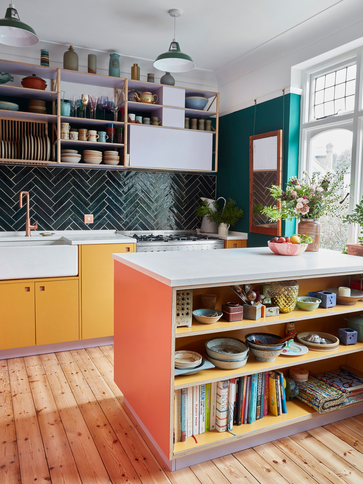 Colourful Pluck kitchen including coral pink, mustard yellow and lilac cabinetry with glossy green tiles and walls.