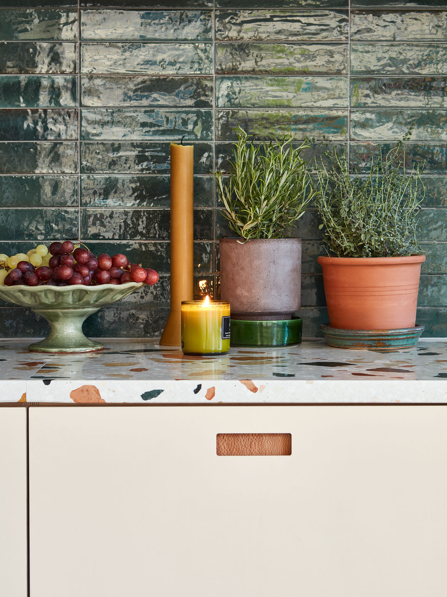Pink, white and wood kitchen with a green tile splashback and warm wood floor.