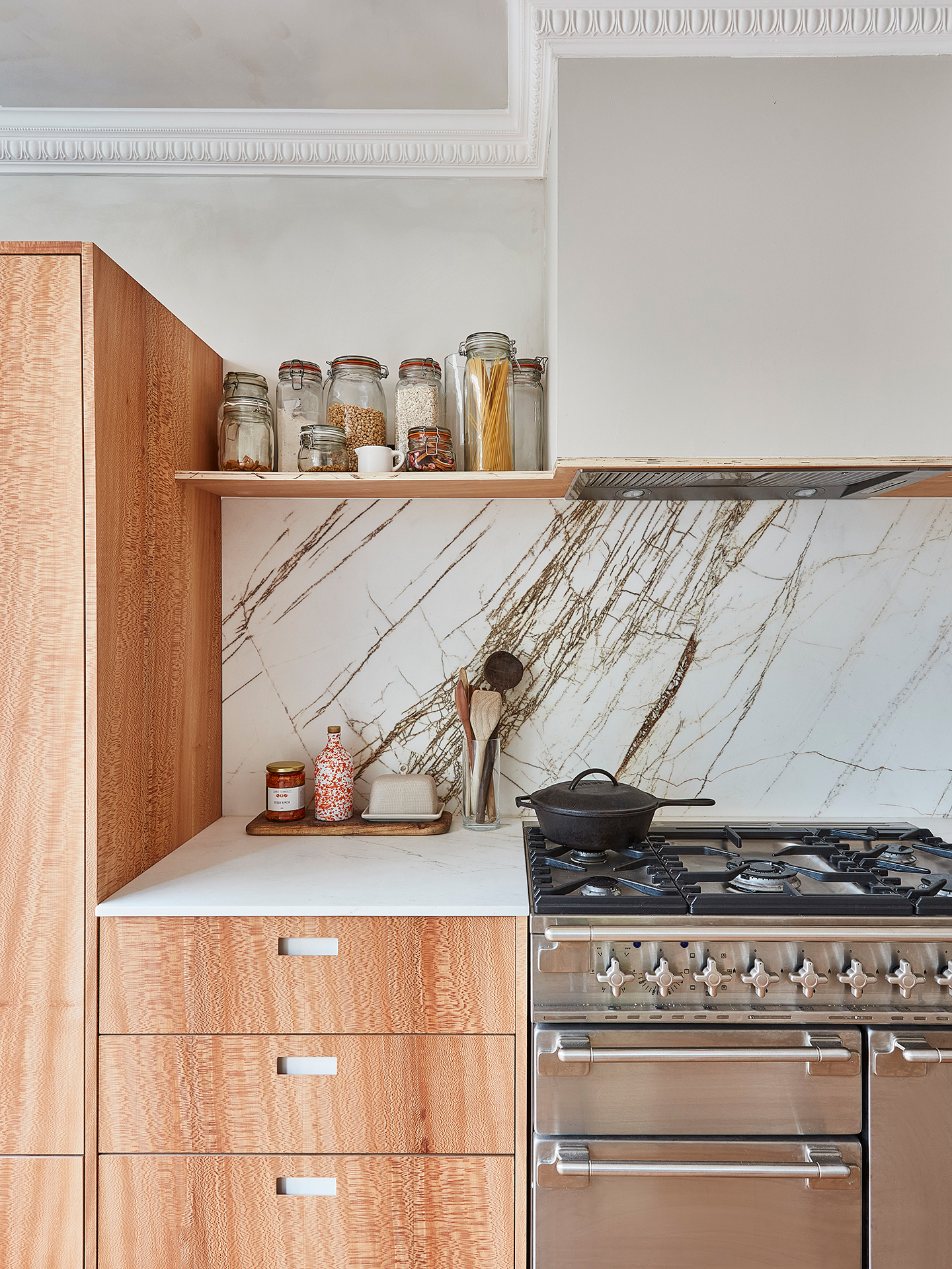 Calming neutral kitchen including London Plane wood and white handmade cabinetry topped with natural stone.