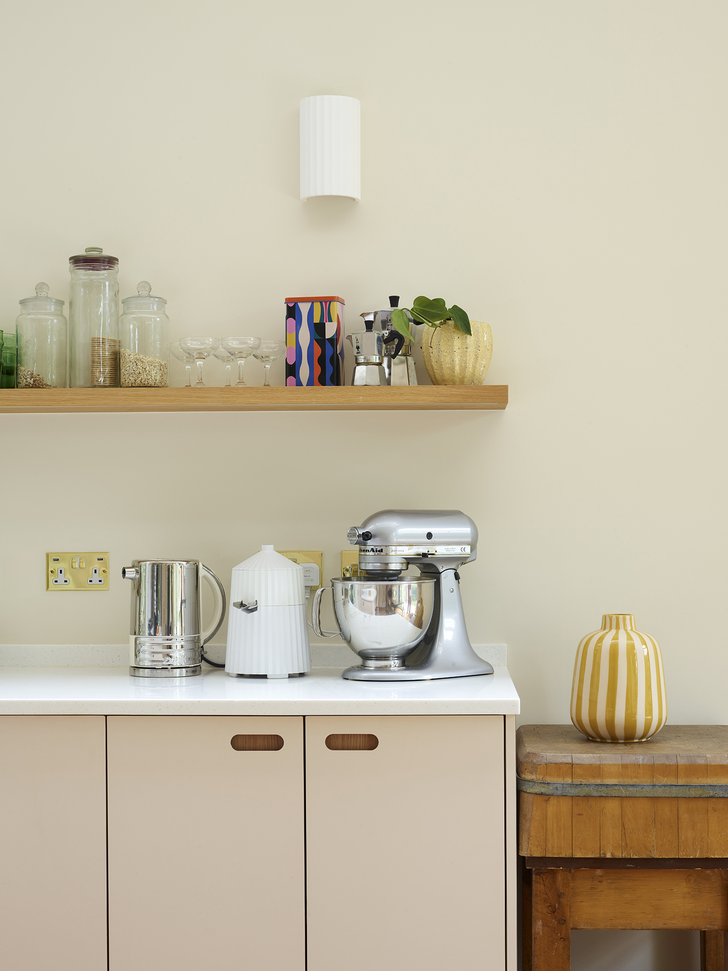 Neutral hues in an open plan family kitchen with a larder, island, dining table and green glazing.