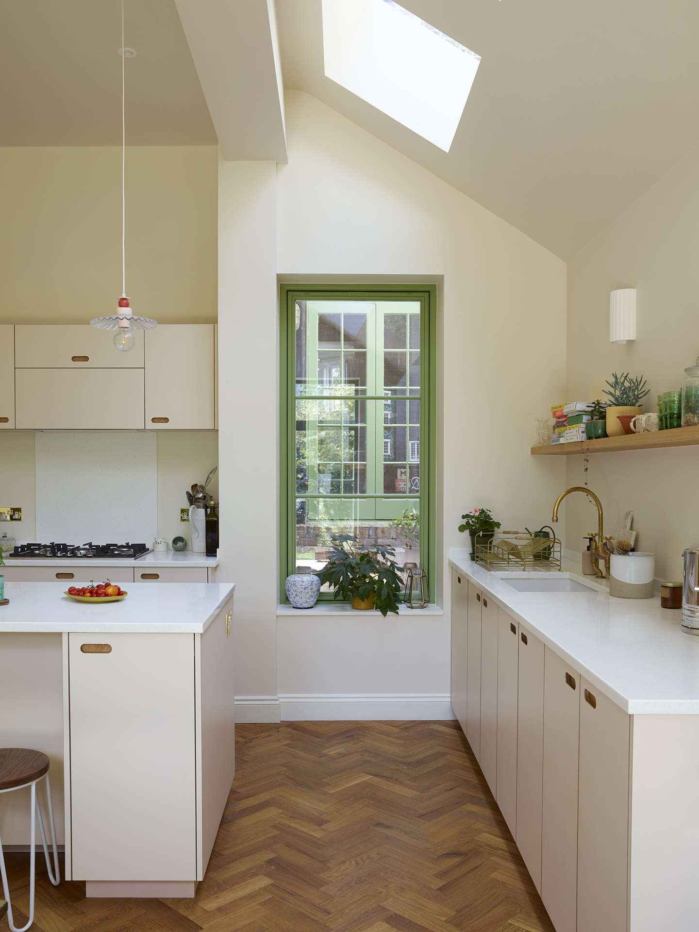 Neutral hues in an open plan family kitchen with a larder, island, dining table and green glazing.