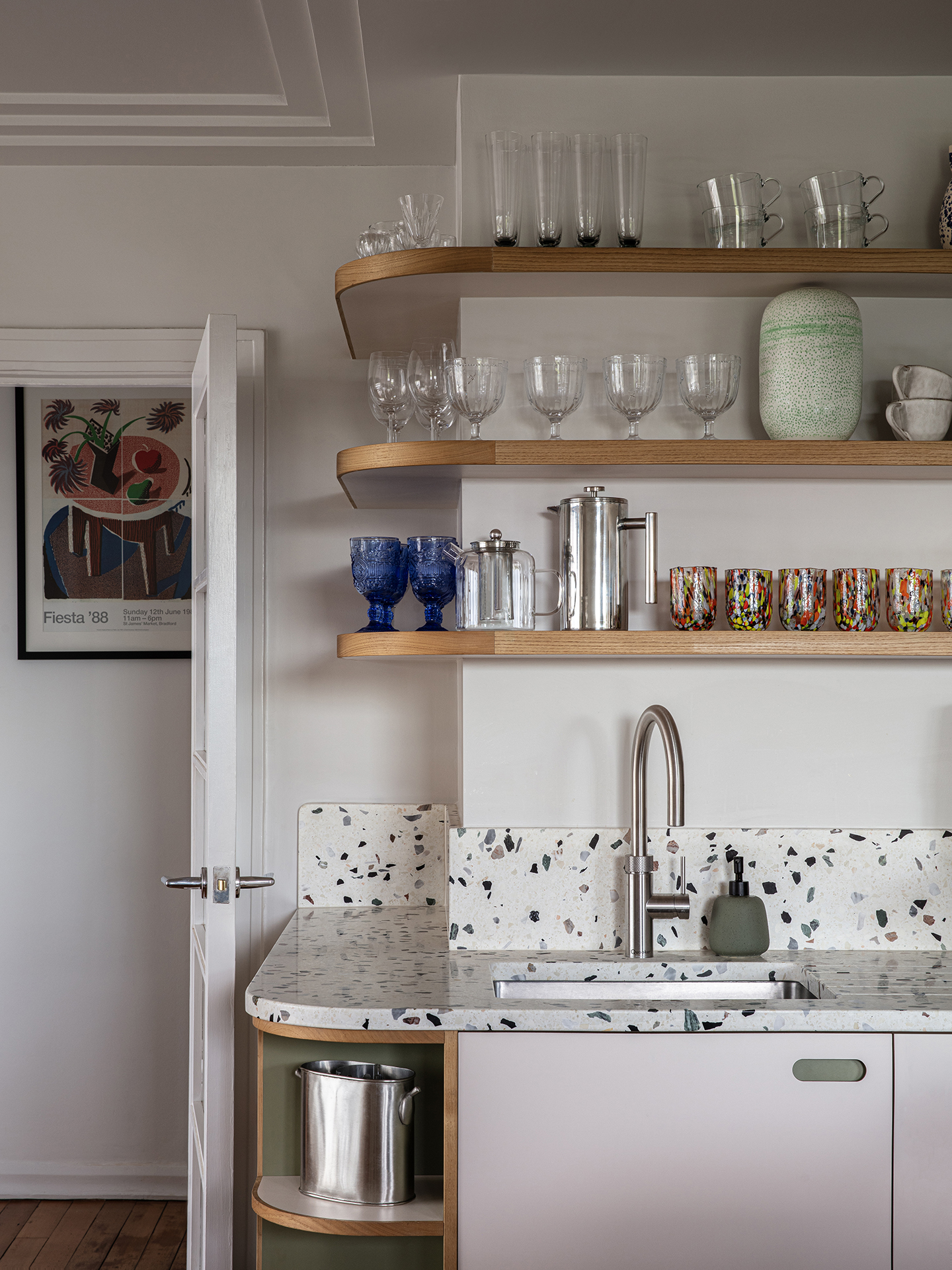 Neutral Pluck kitchen with curved shelving, an island and seating in a seaside bolthole for family and friends.