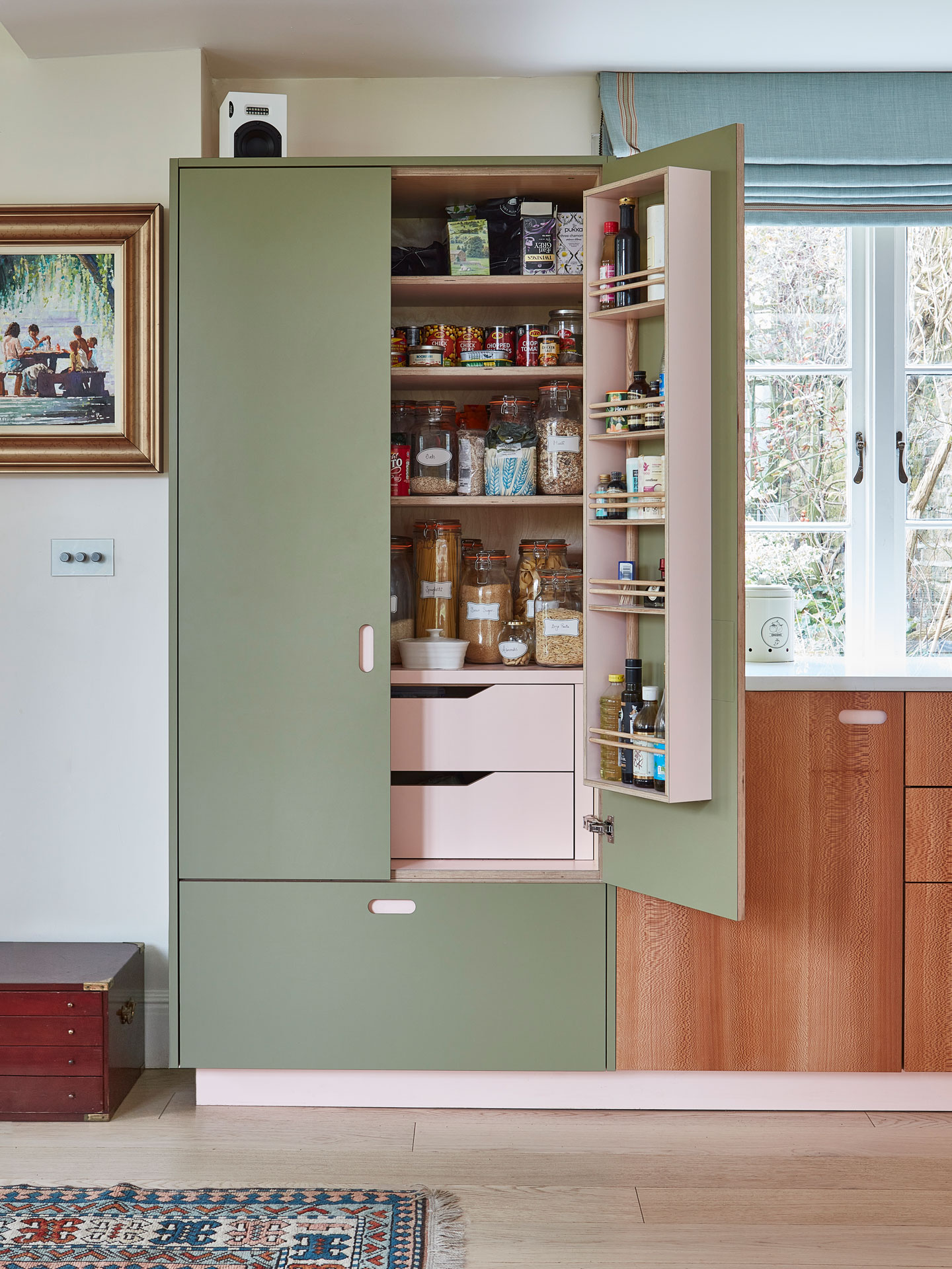 A soft green and pale pink larder with London Plane wood cabinetry.