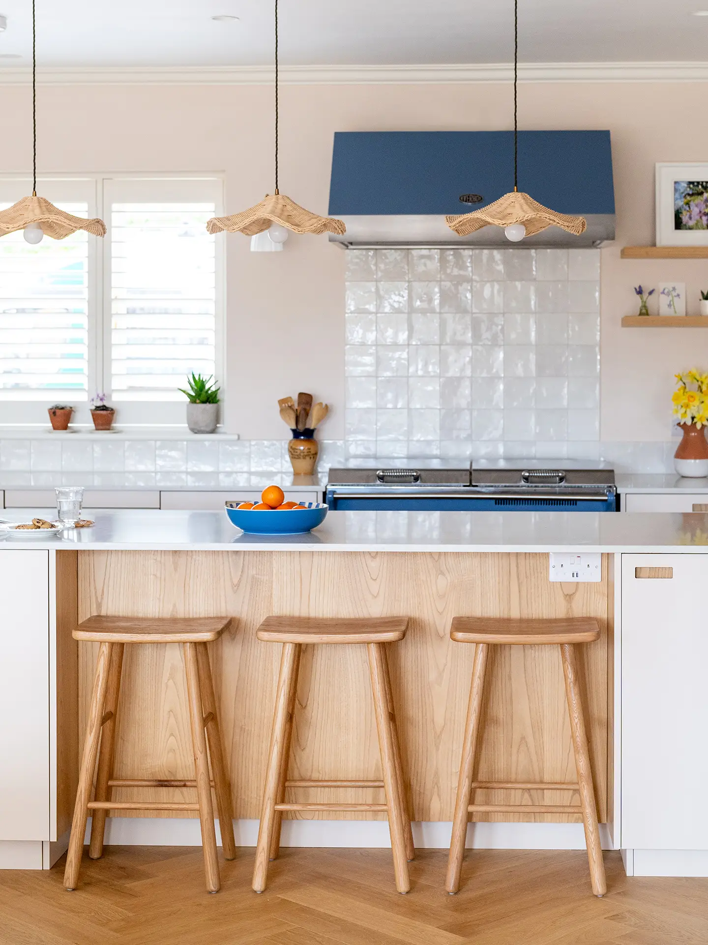 Neutral hues and Sweet Chestnut wood in an open plan kitchen in Guildford with an island and blue Everhot range cooker.