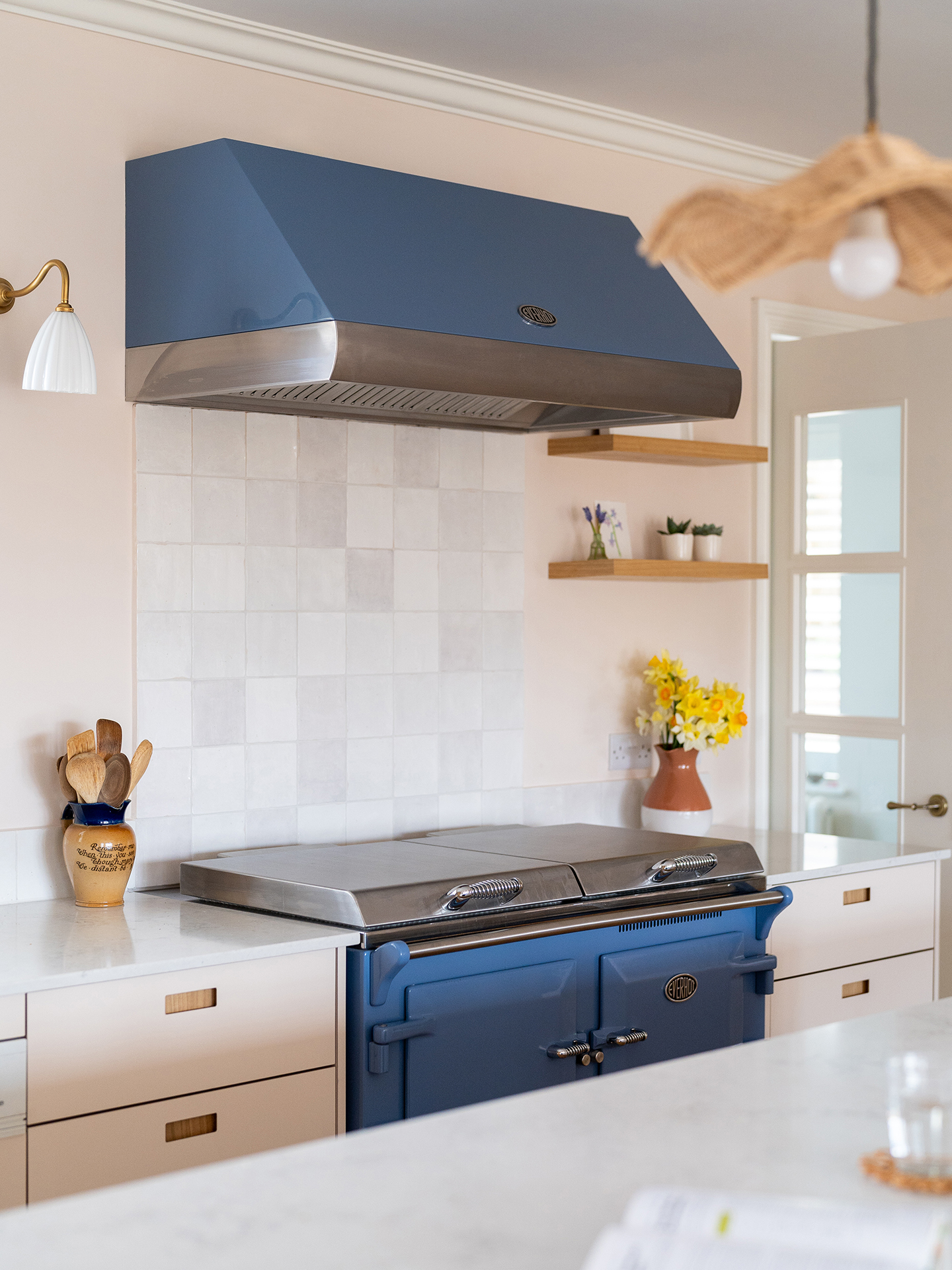 Neutral hues and Sweet Chestnut wood in an open plan kitchen in Guildford with an island and blue Everhot range cooker.