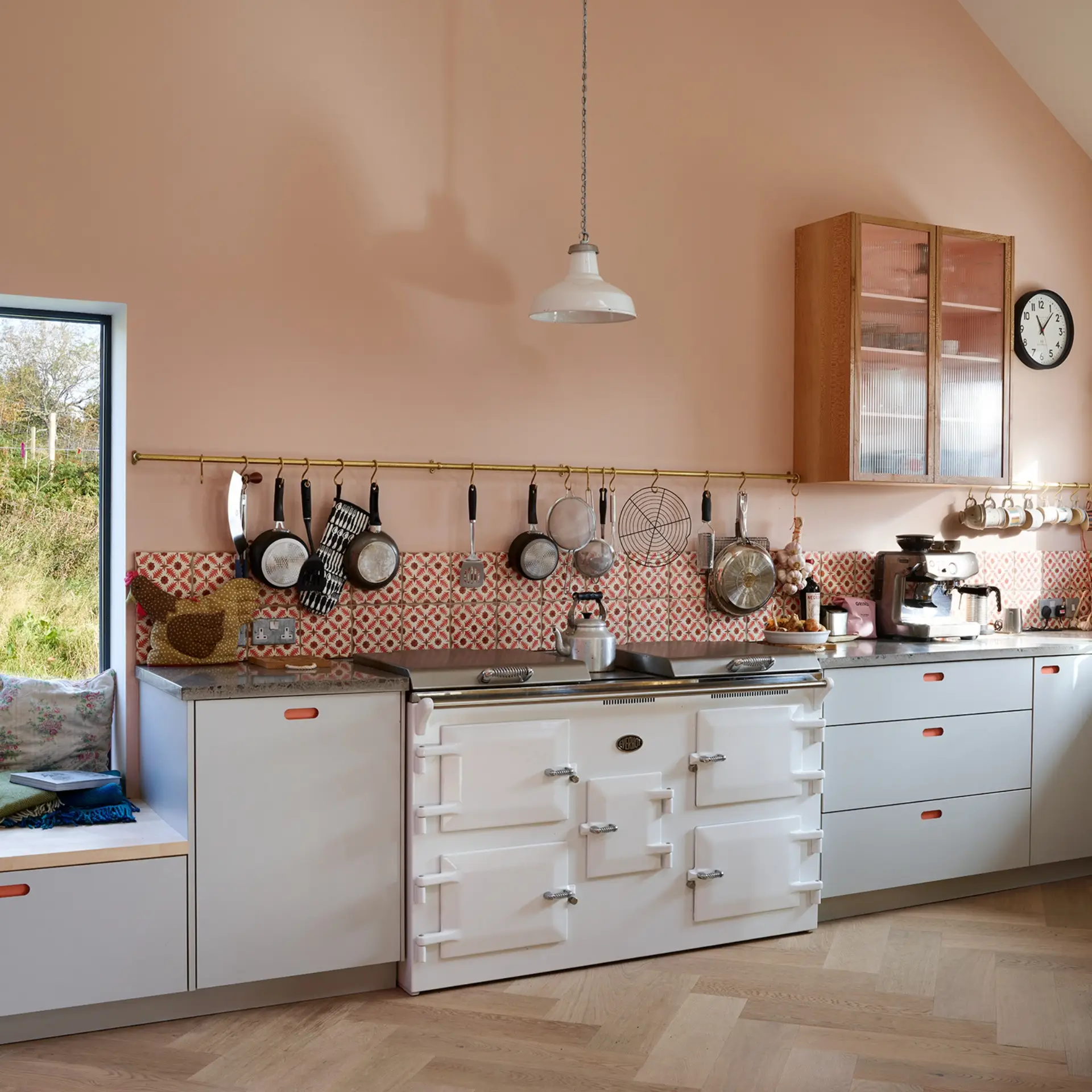 Colourful open plan kitchen in the Scottish Highlands including a peninsula with a wooden worktop, shelving, glass cabinet and Pluck utility.