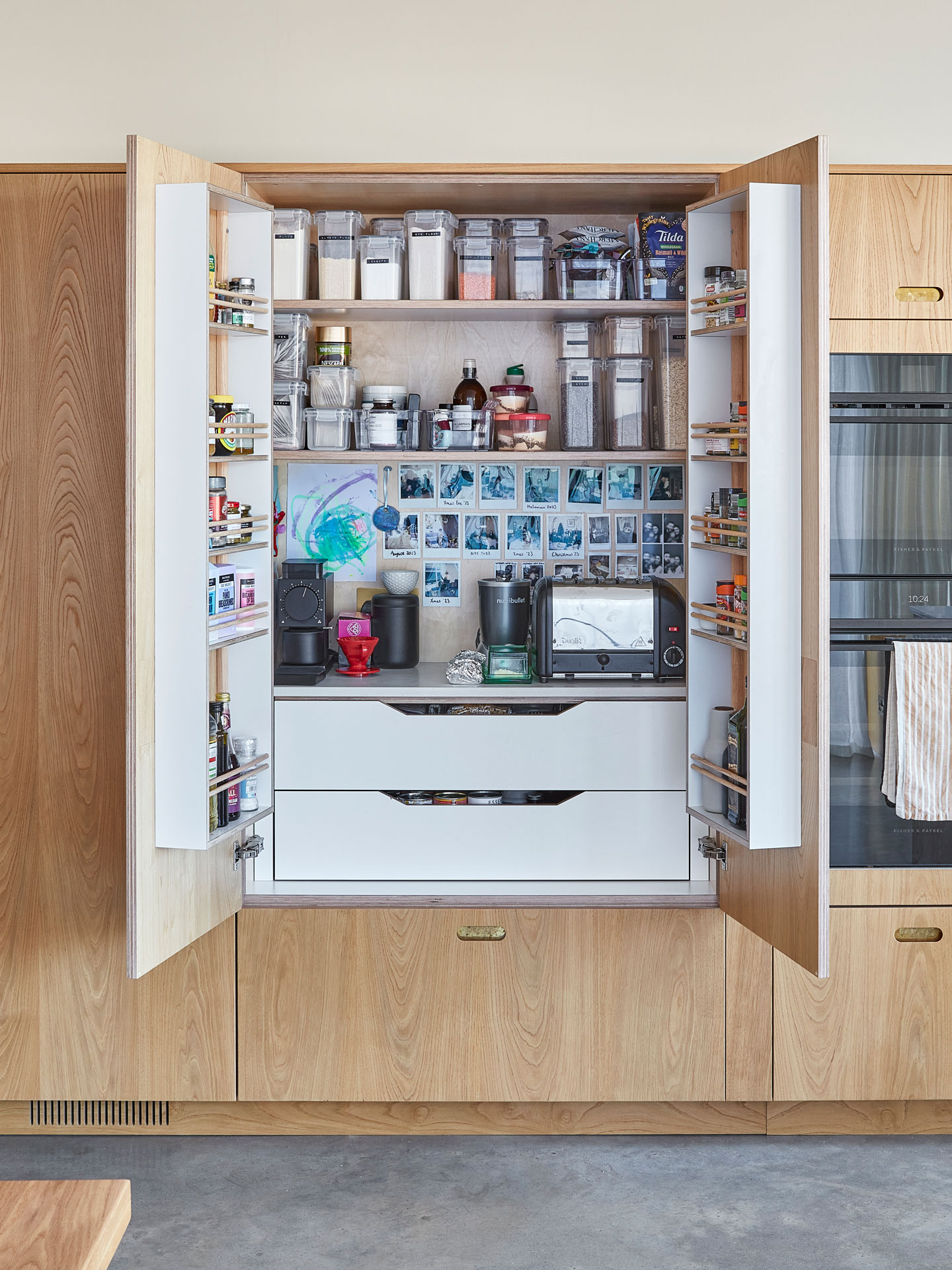 Pluck's wood veneered cabinetry in a Scandi chic open plan family kitchen with concrete floors.