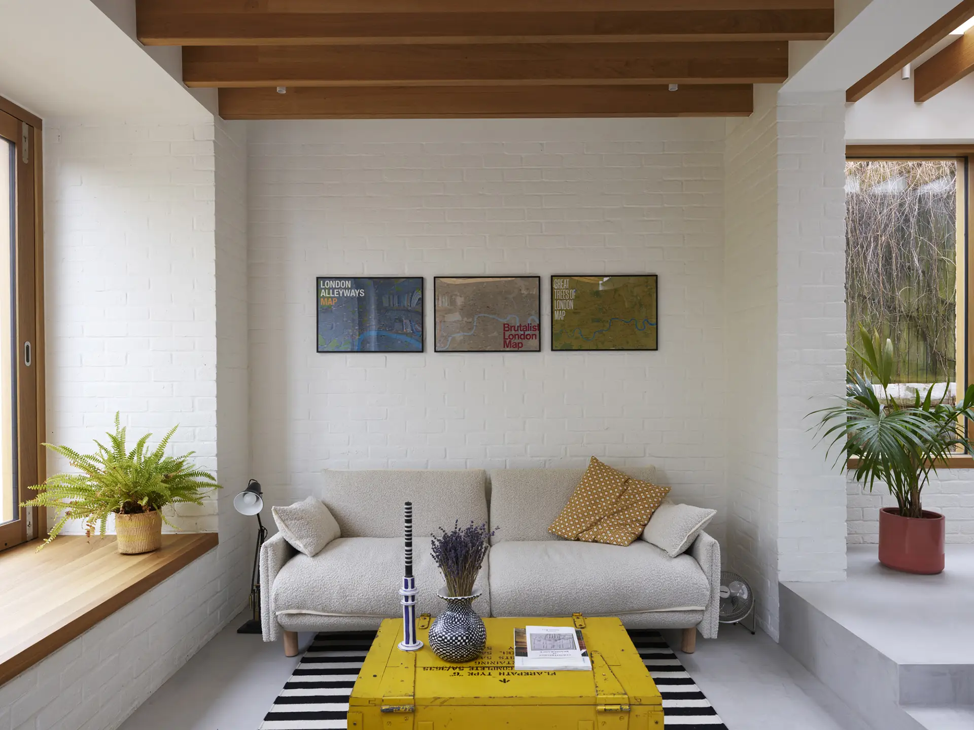 Cosy sofa in an architect's minimalist home with wooden beams and exposed bricks.