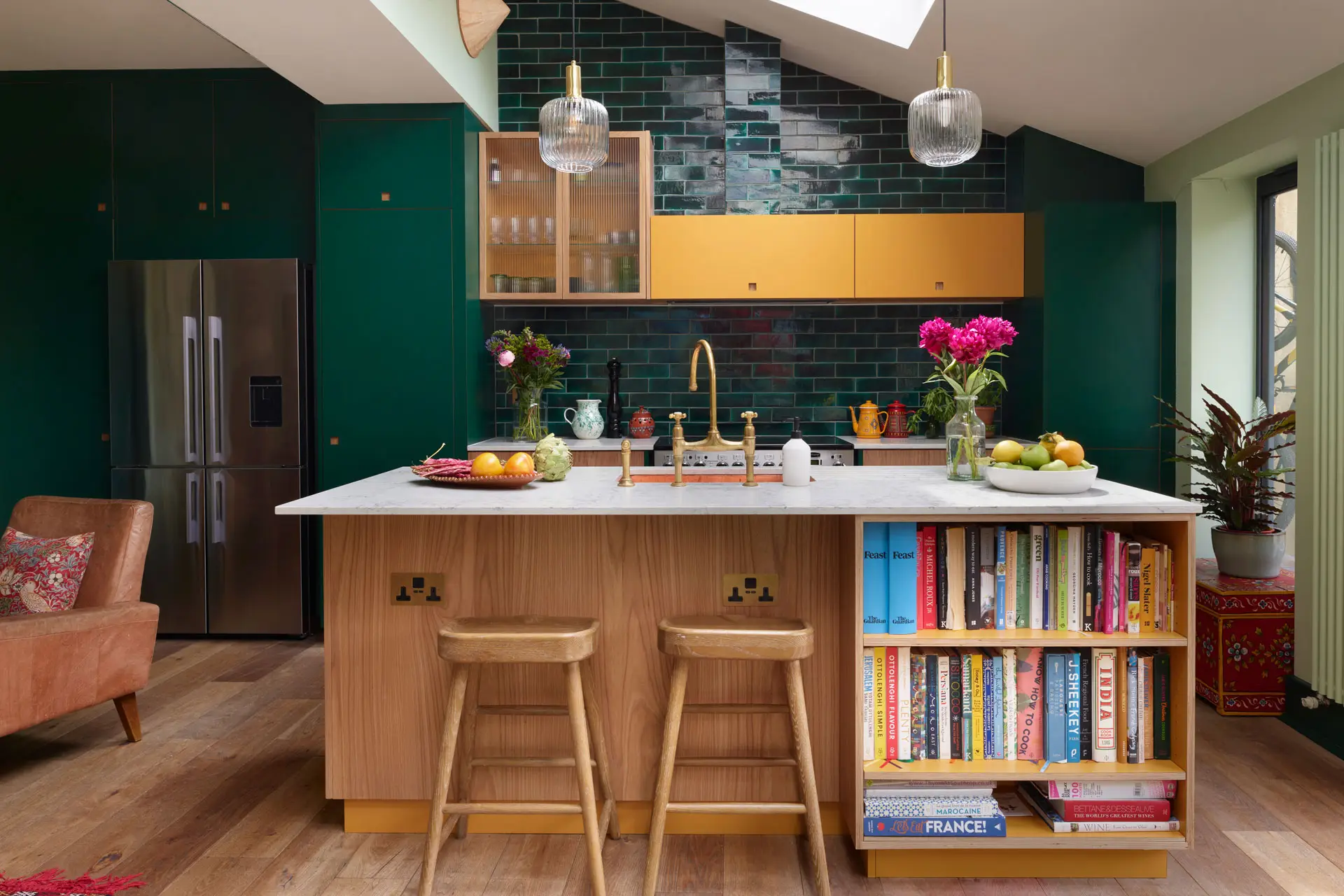 Kitchen home to an artist including dark green, Elm wood and mustard yellow cabinets, glossy tiles and pale palm green walls.