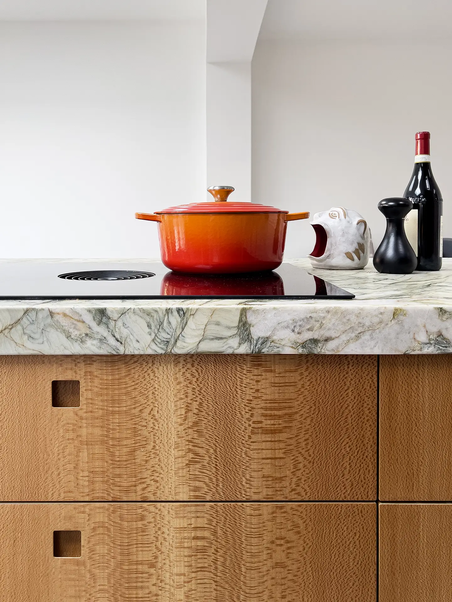 Blue, pink and warm wood Pluck kitchen including an island with quartzite and mirror splashback.