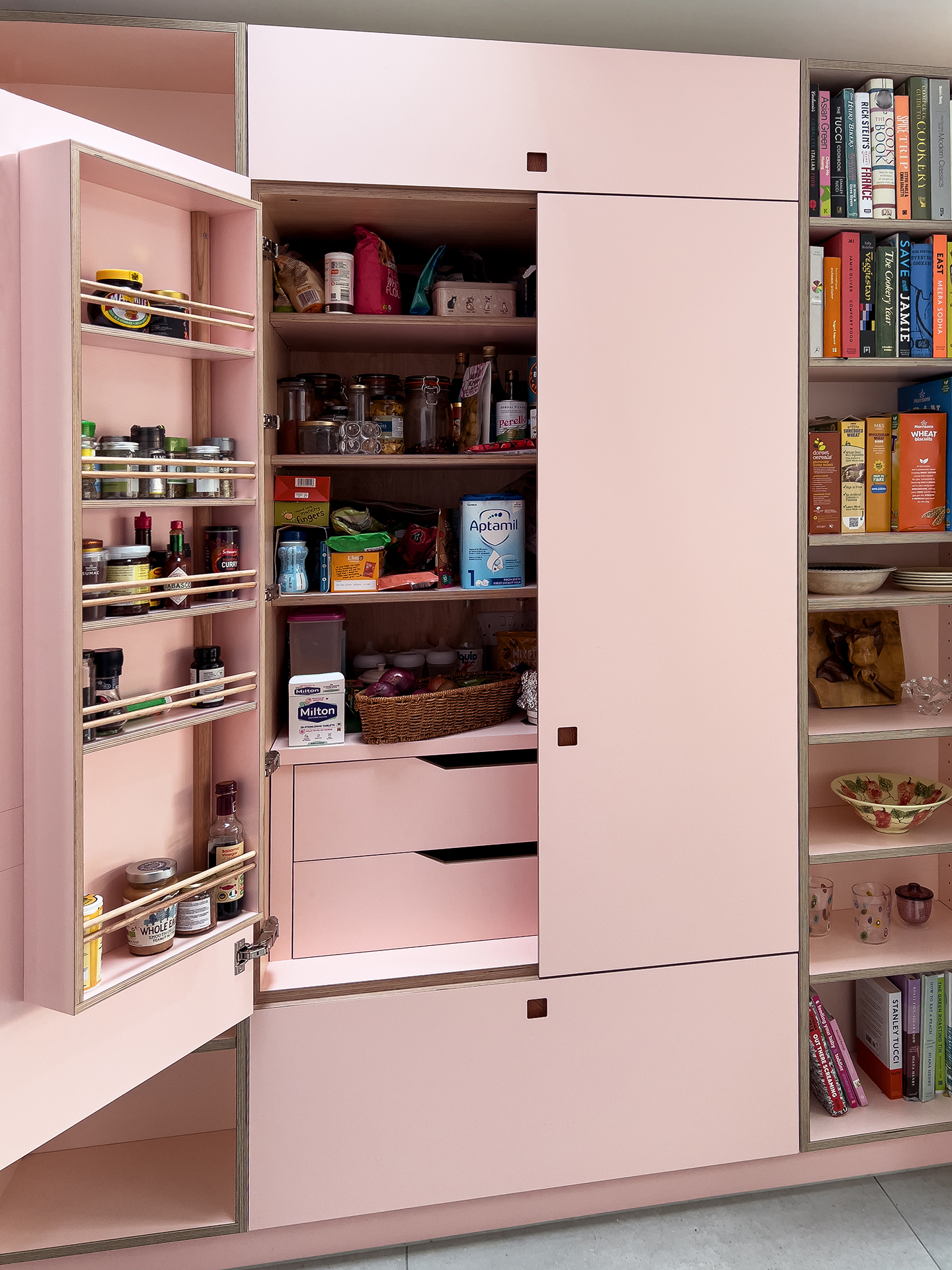 Larder in a blue, pink and warm wood Pluck kitchen including an island with quartzite and mirror splashback.