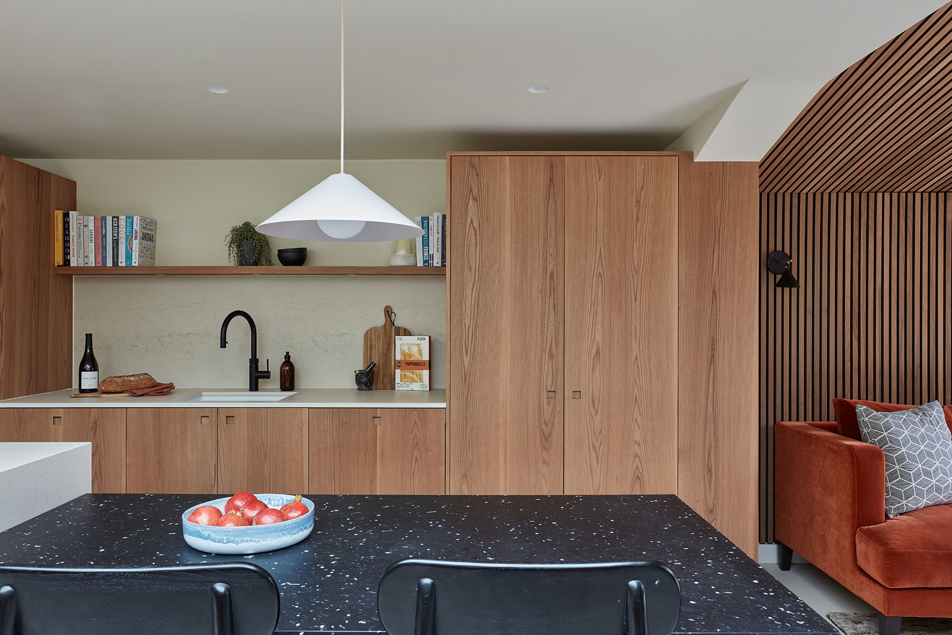 Elm wood family kitchen with a waterfall edge island for keen cooks and custom shallow cabinets for children's toys and crafts.