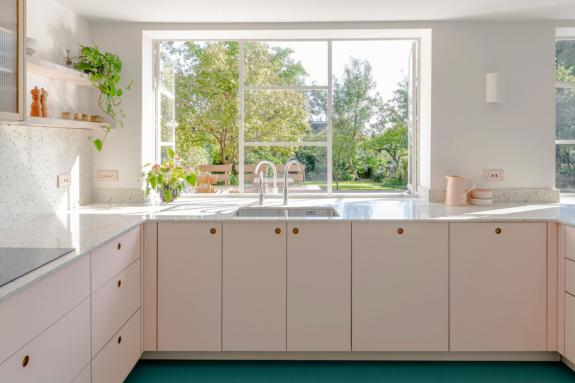 Pastel pink and beige Pluck cabinetry in an open plan space with a bright blue floor.